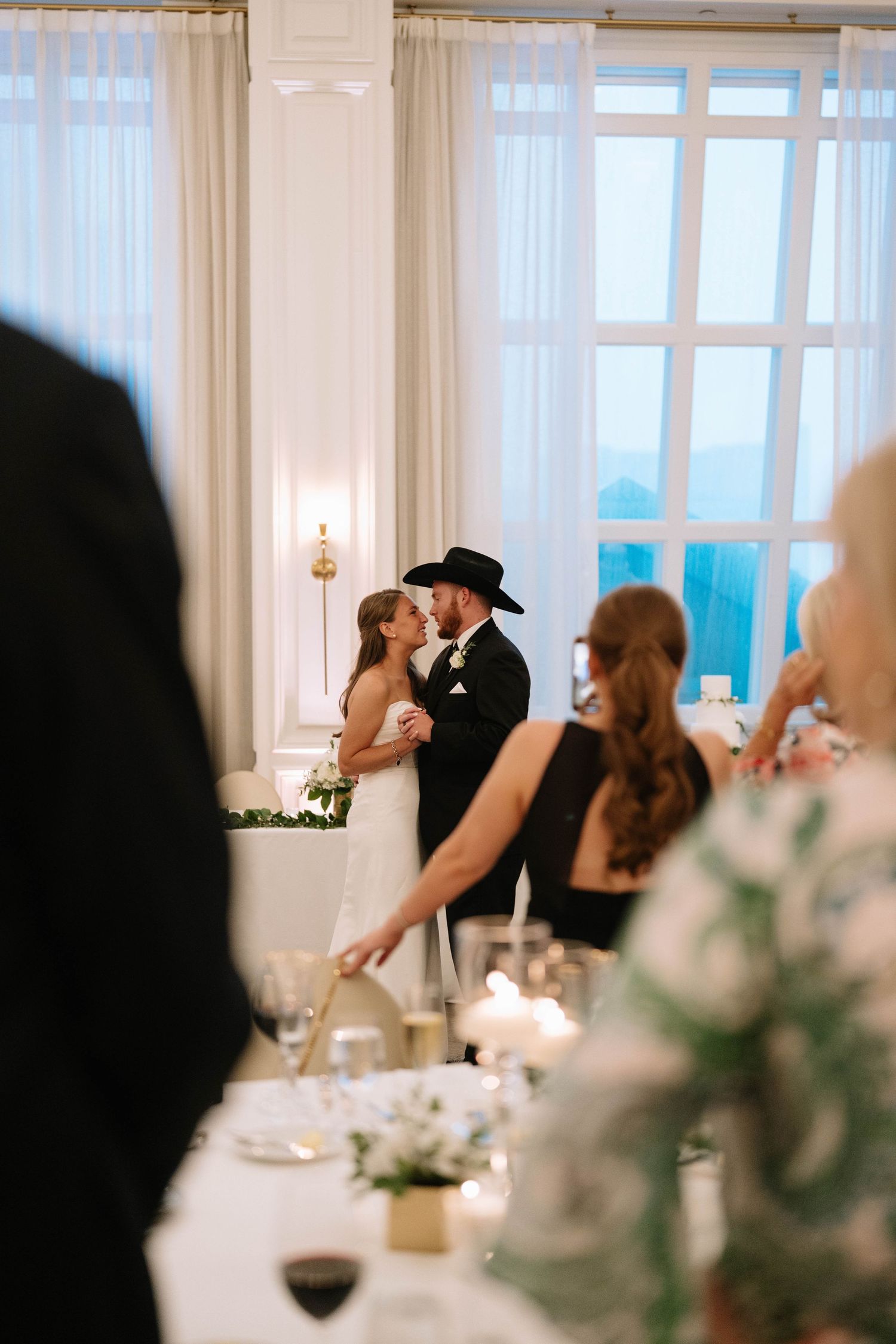 Romantic wedding reception dance captured in an elegant white ballroom.