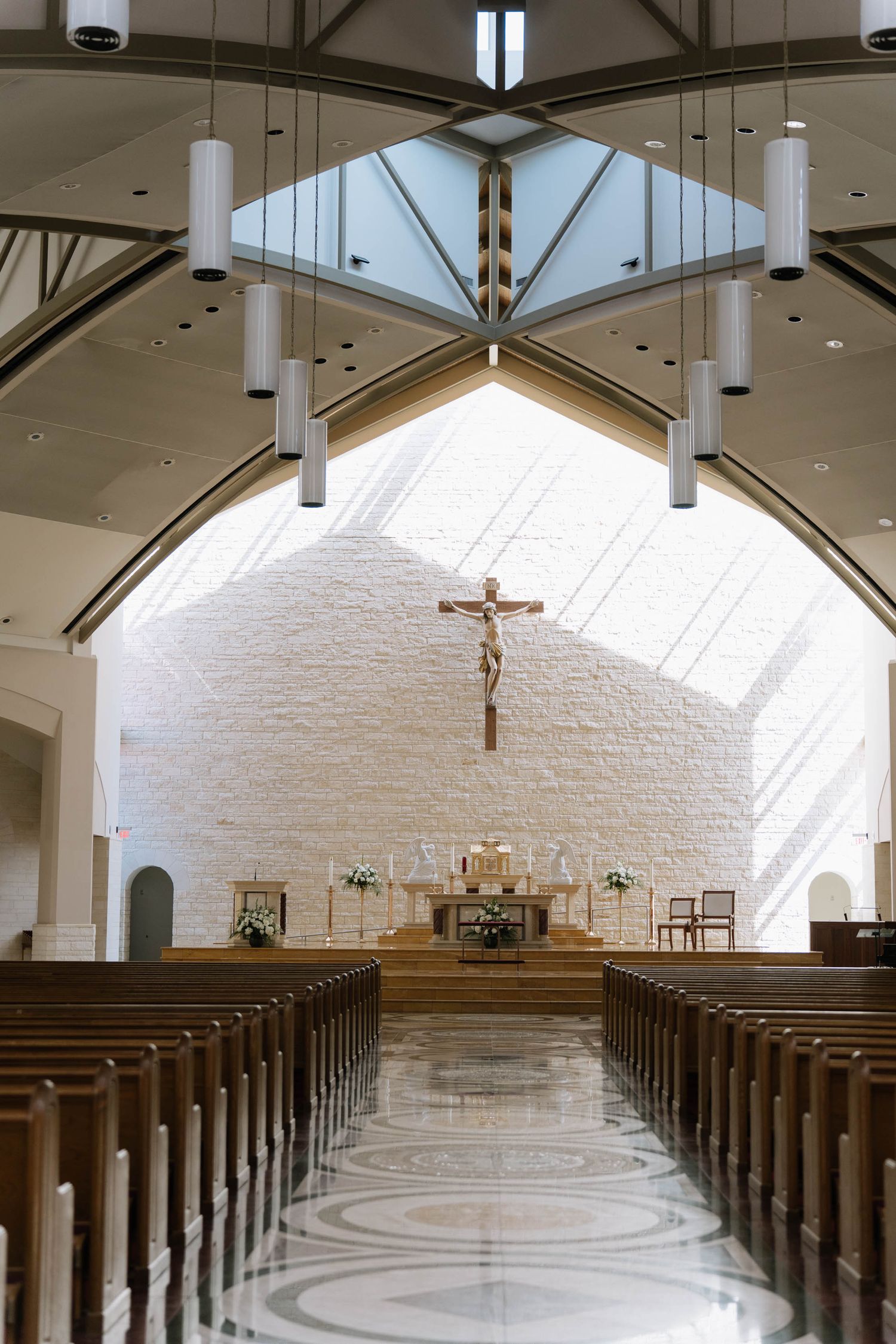 Modern church interior with white walls, wooden pews, and natural light streaming through skylights.