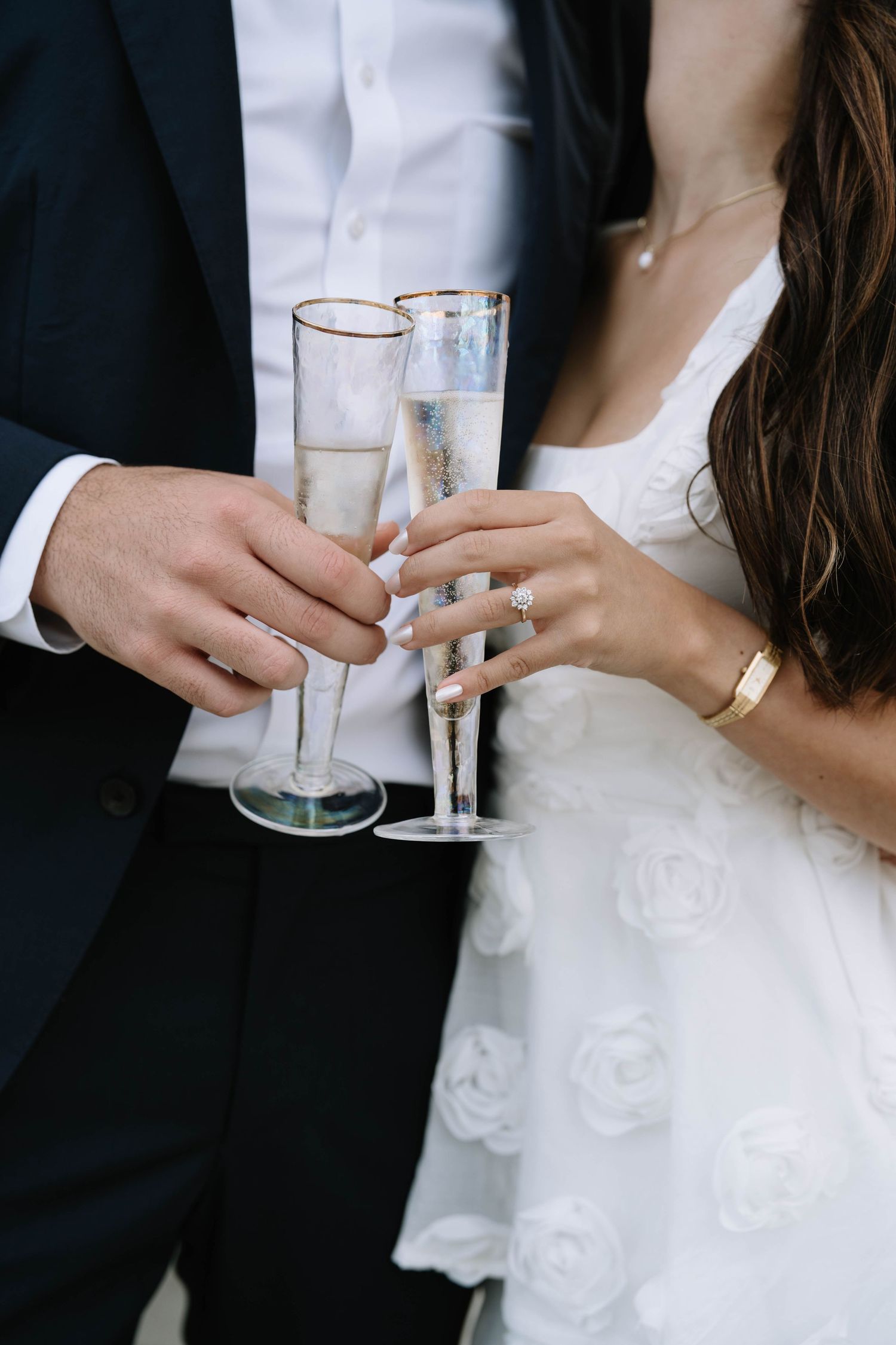 Close-up of champagne glasses clinking at a wedding celebration.