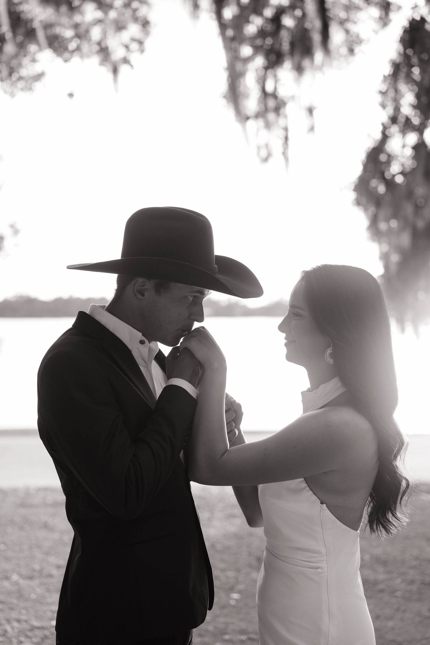 A romantic black and white portrait of a couple in formal attire at sunset.
