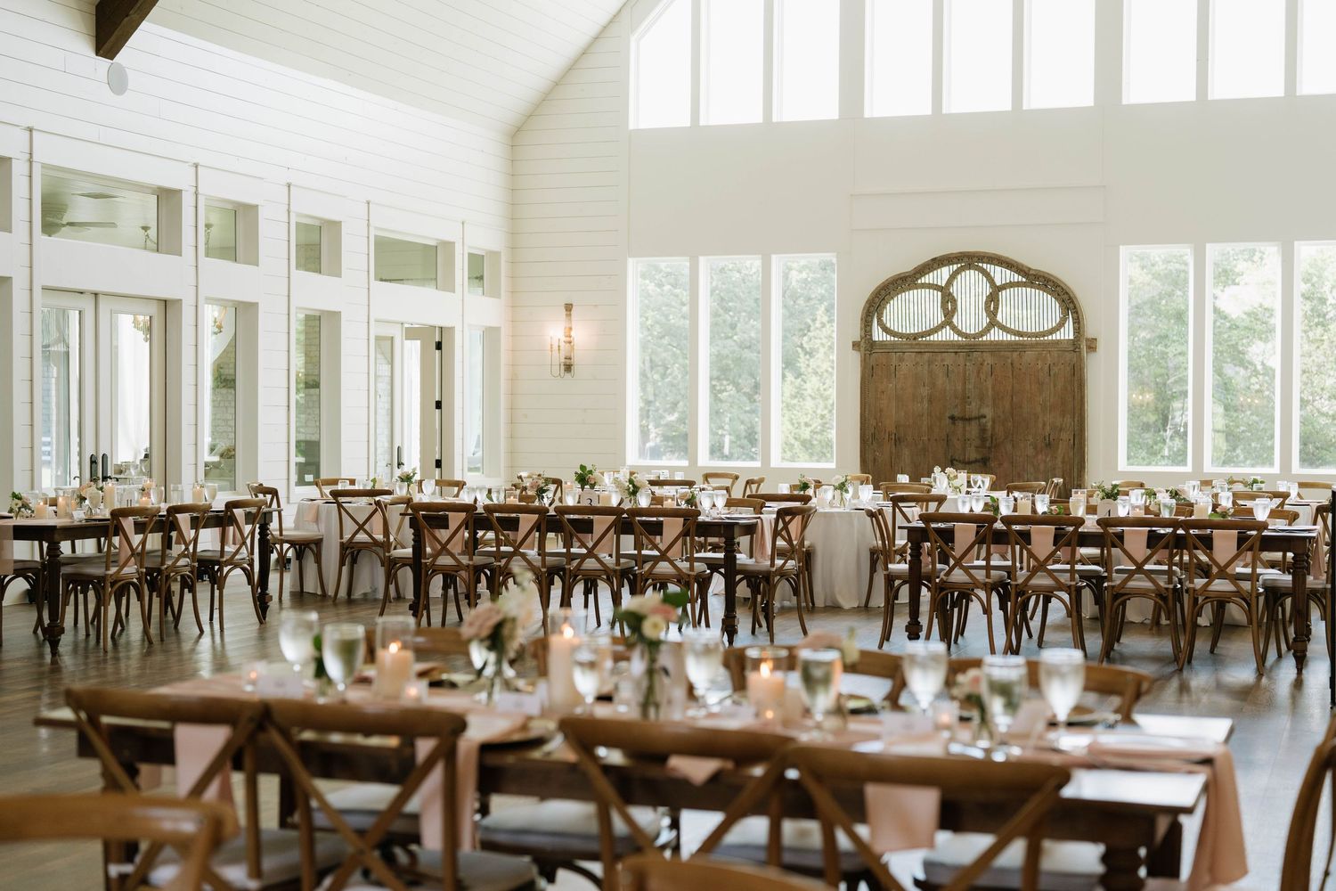 A bright reception hall with wooden cross-back chairs and large windows creating an elegant atmosphere.