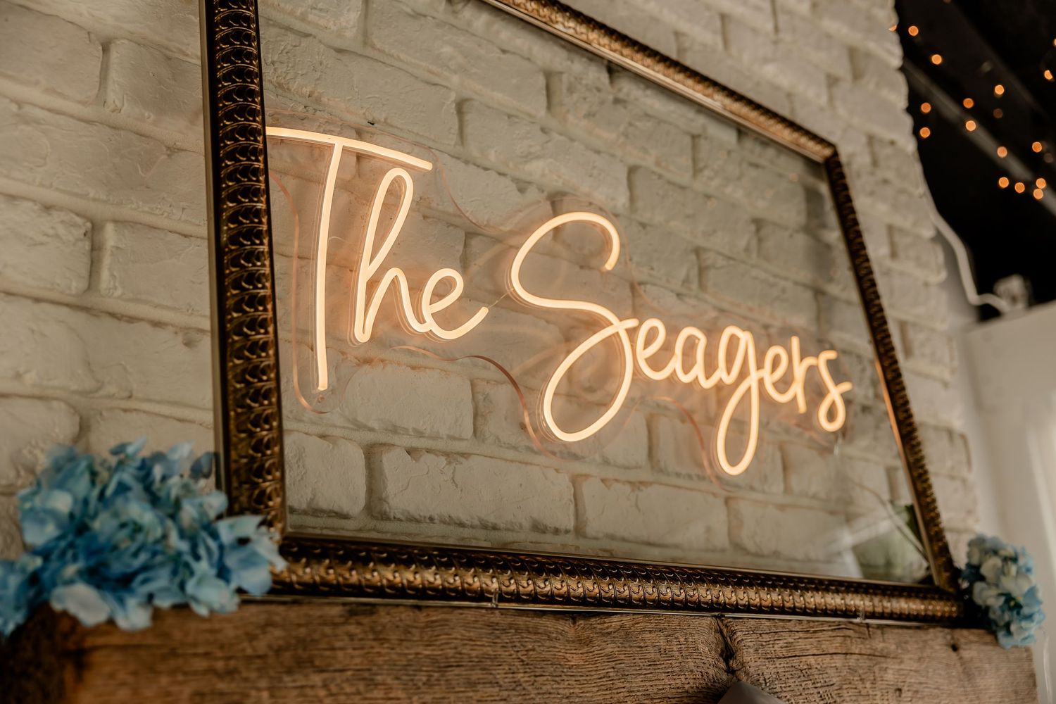 Illuminated neon wedding sign mounted on rustic stone wall.