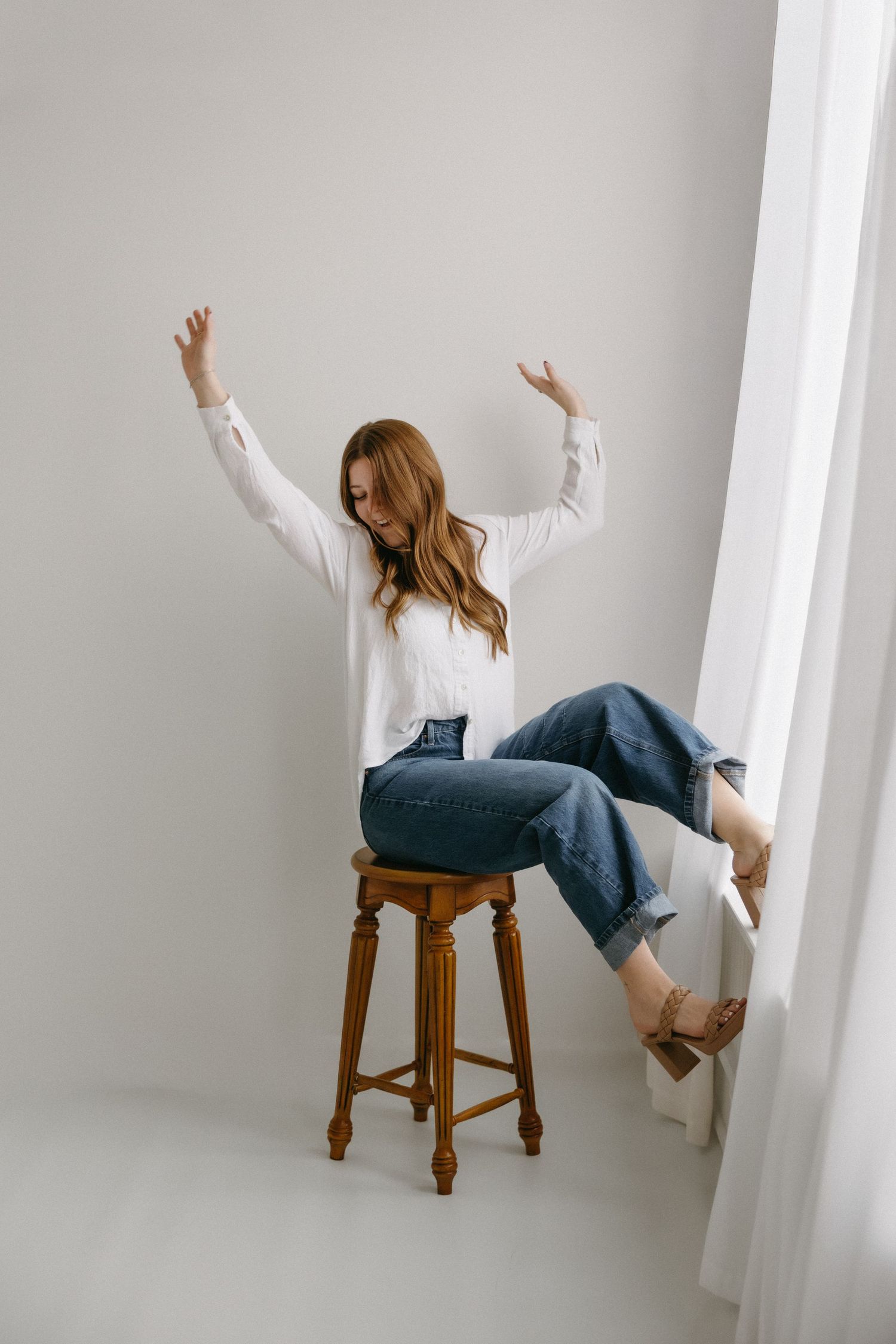 A sequence of photos showing someone playfully falling backwards off a wooden stool in a white room.