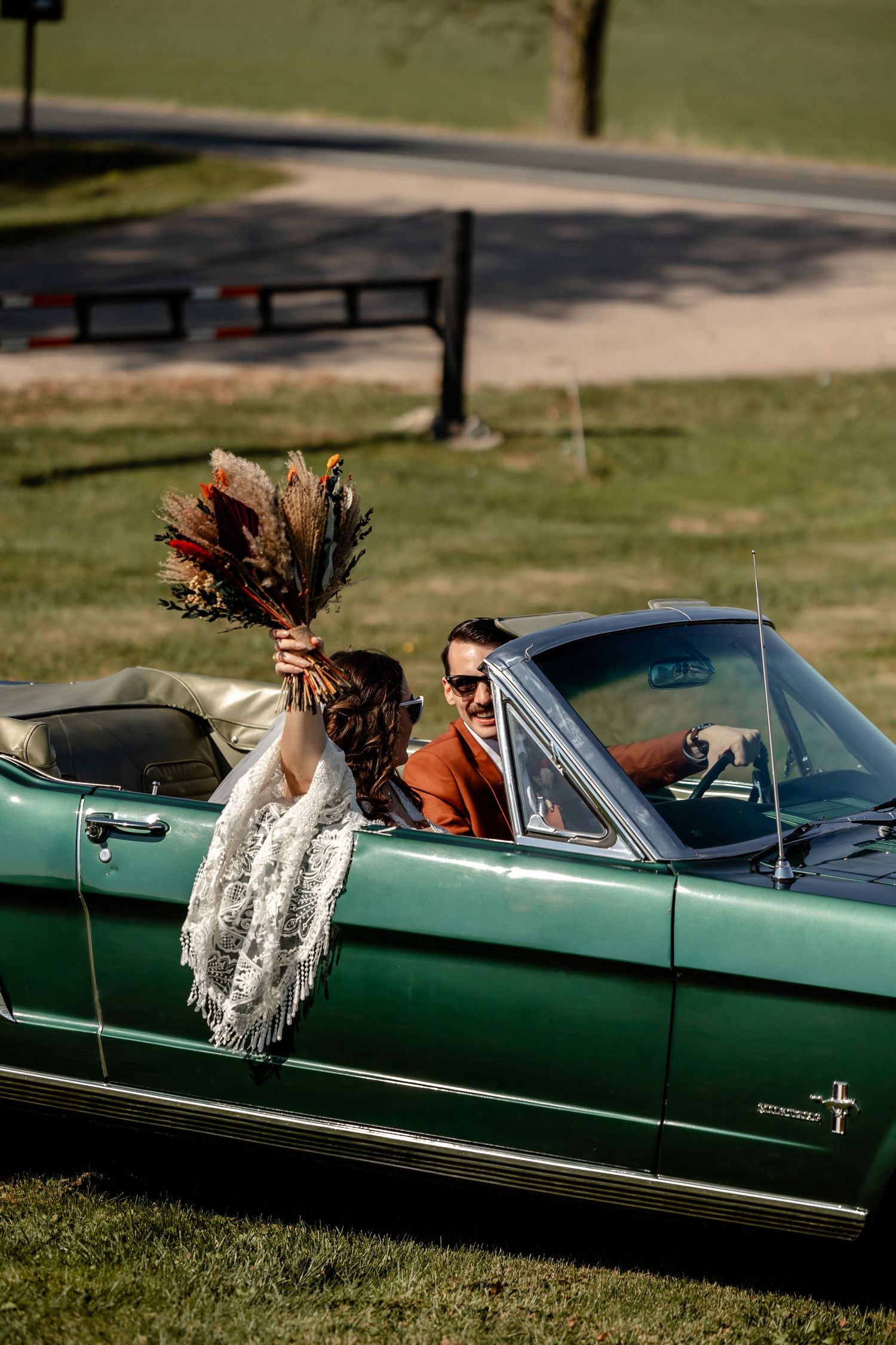 A classic green convertible car with motion blur showing movement on a sunny lawn.