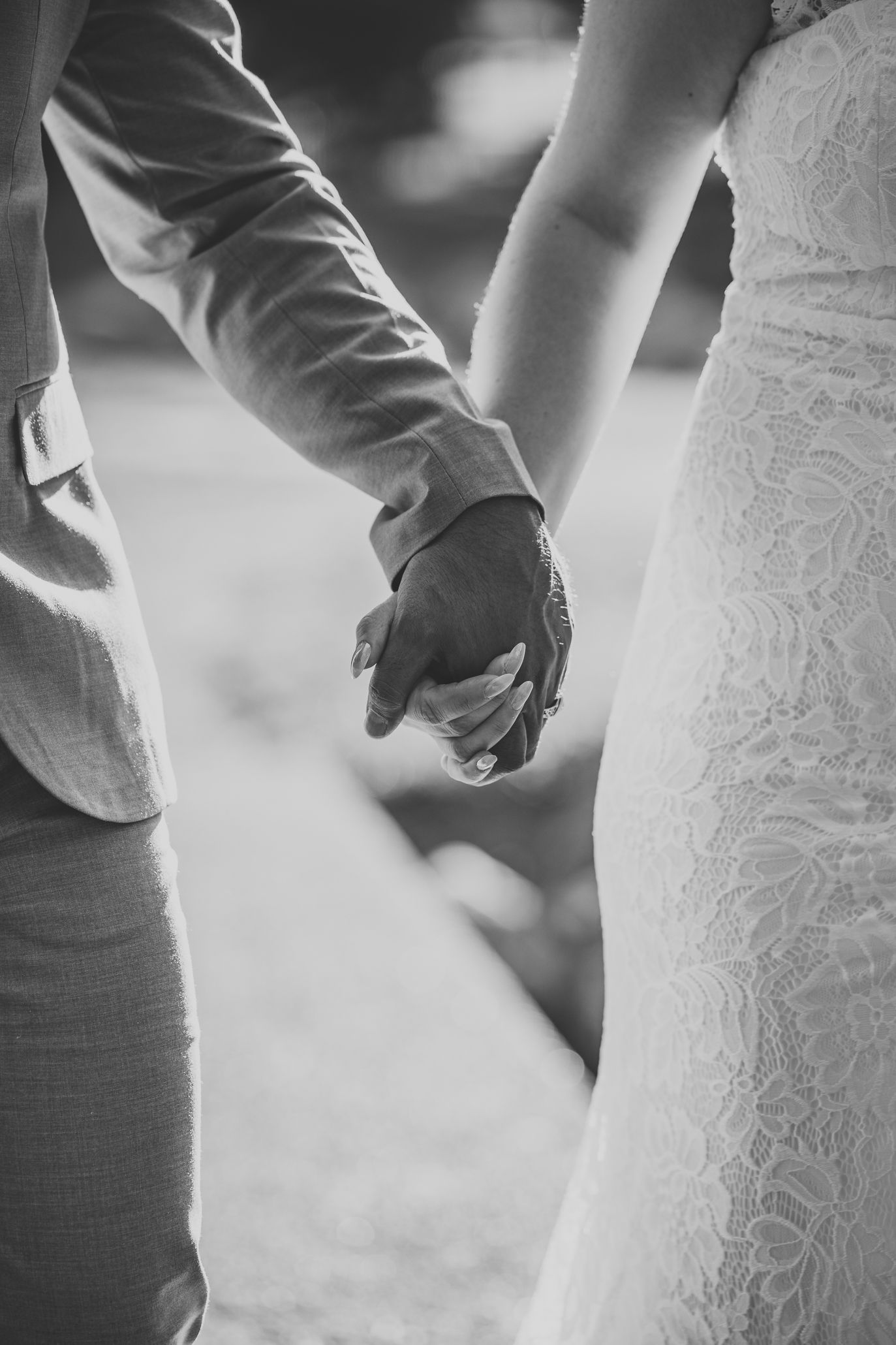 Close-up black and white detail shot showing a bridal gown next to a gray suit.