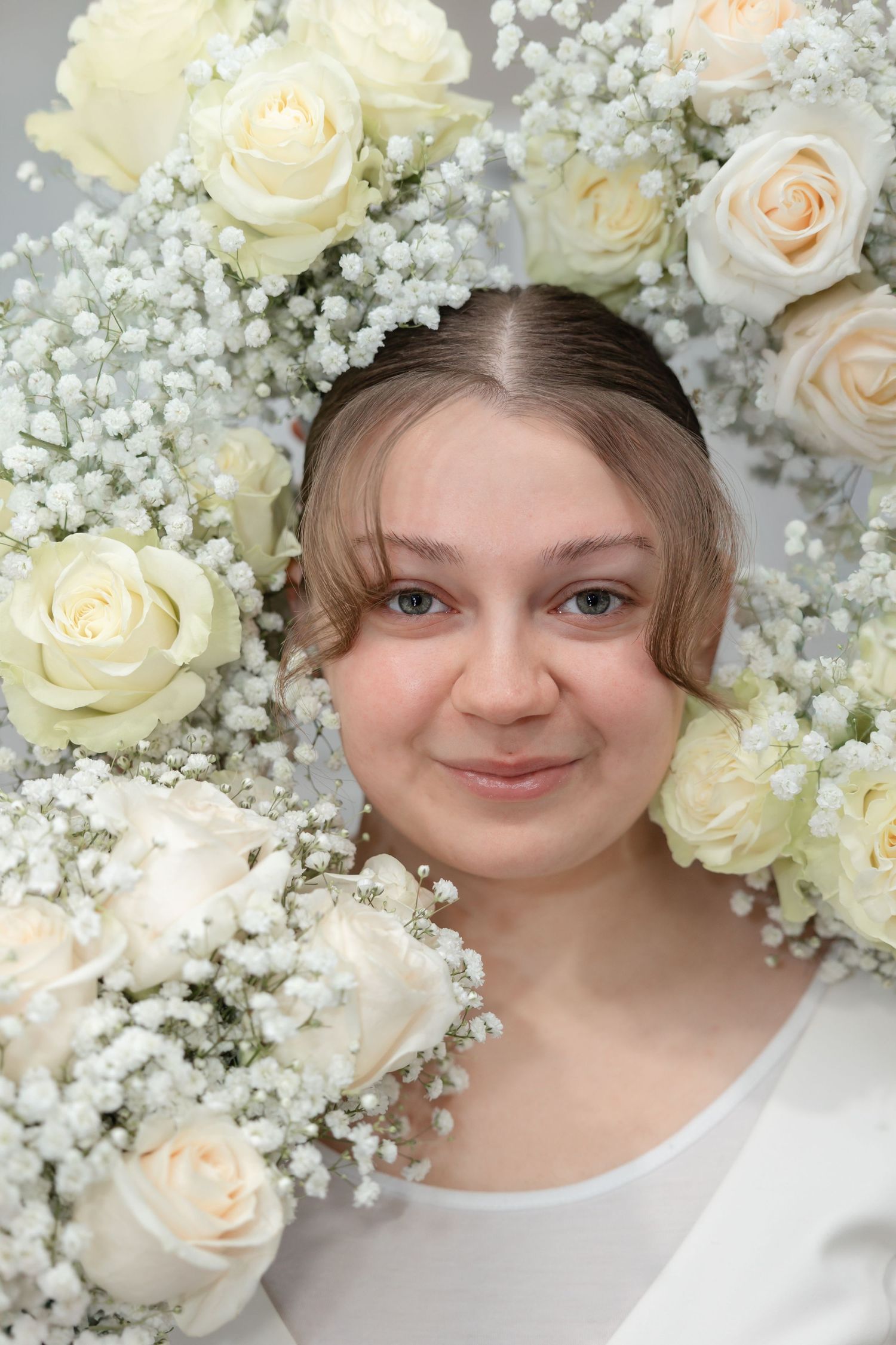 Close up portrait surrounded by delicate white roses and baby's breath flowers creating an ethereal frame.