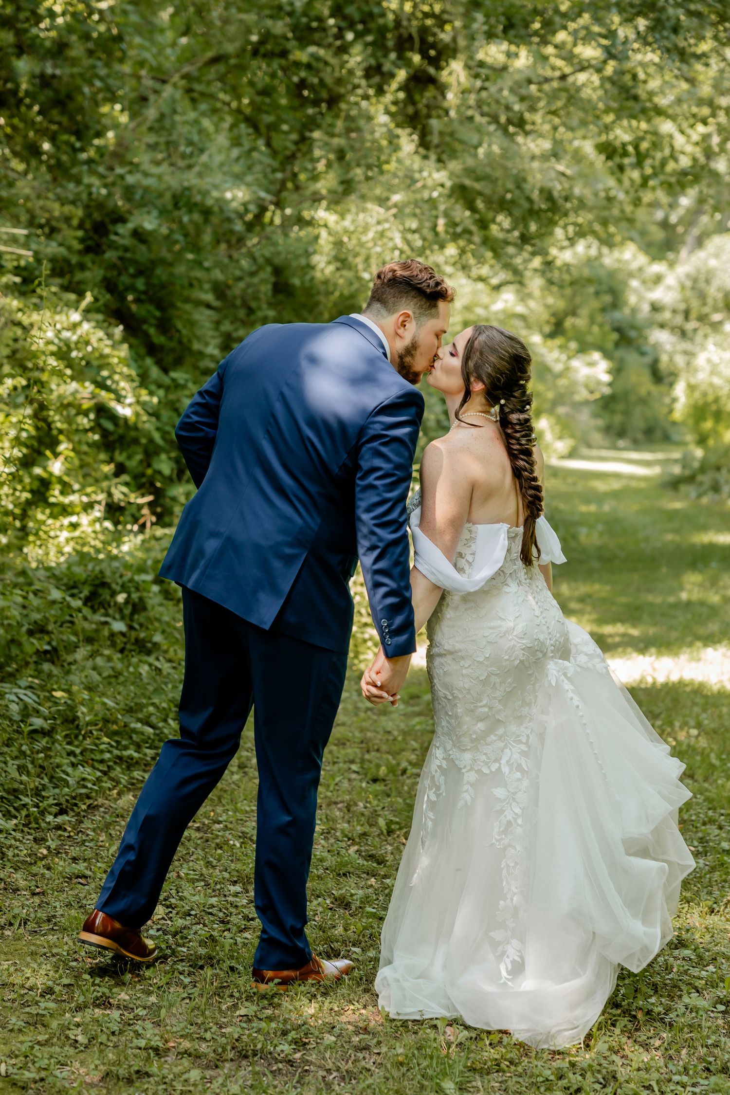 A romantic outdoor wedding photo showing a couple in formal attire sharing an intimate moment in a garden setting.