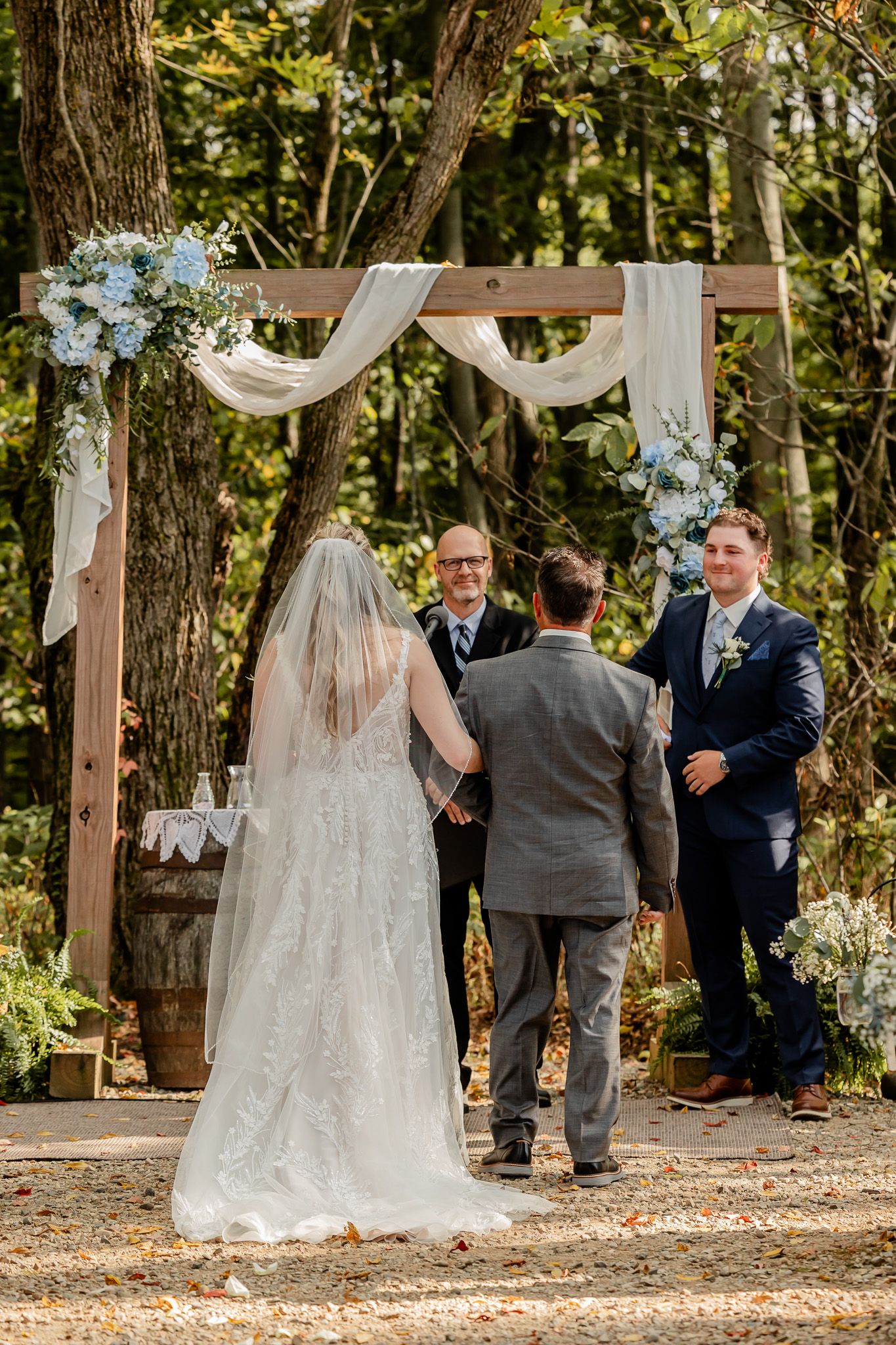 A series of outdoor wedding ceremony shots showing guests gathered under trees with wooden arch decorations.