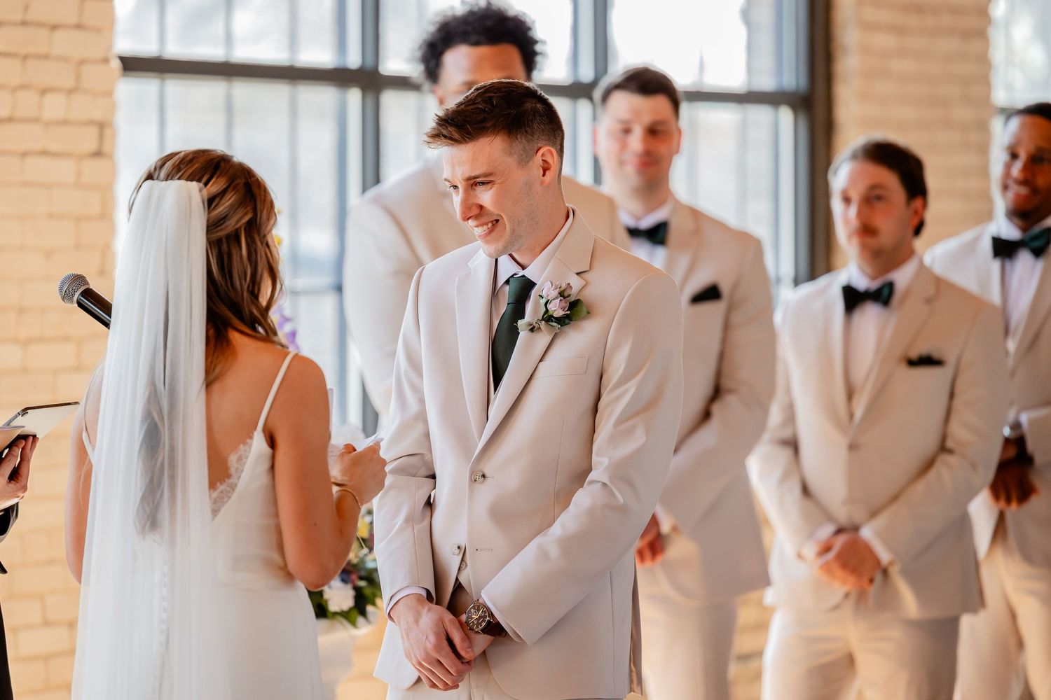 Wedding party in cream-colored attire gathered in an elegant indoor setting.