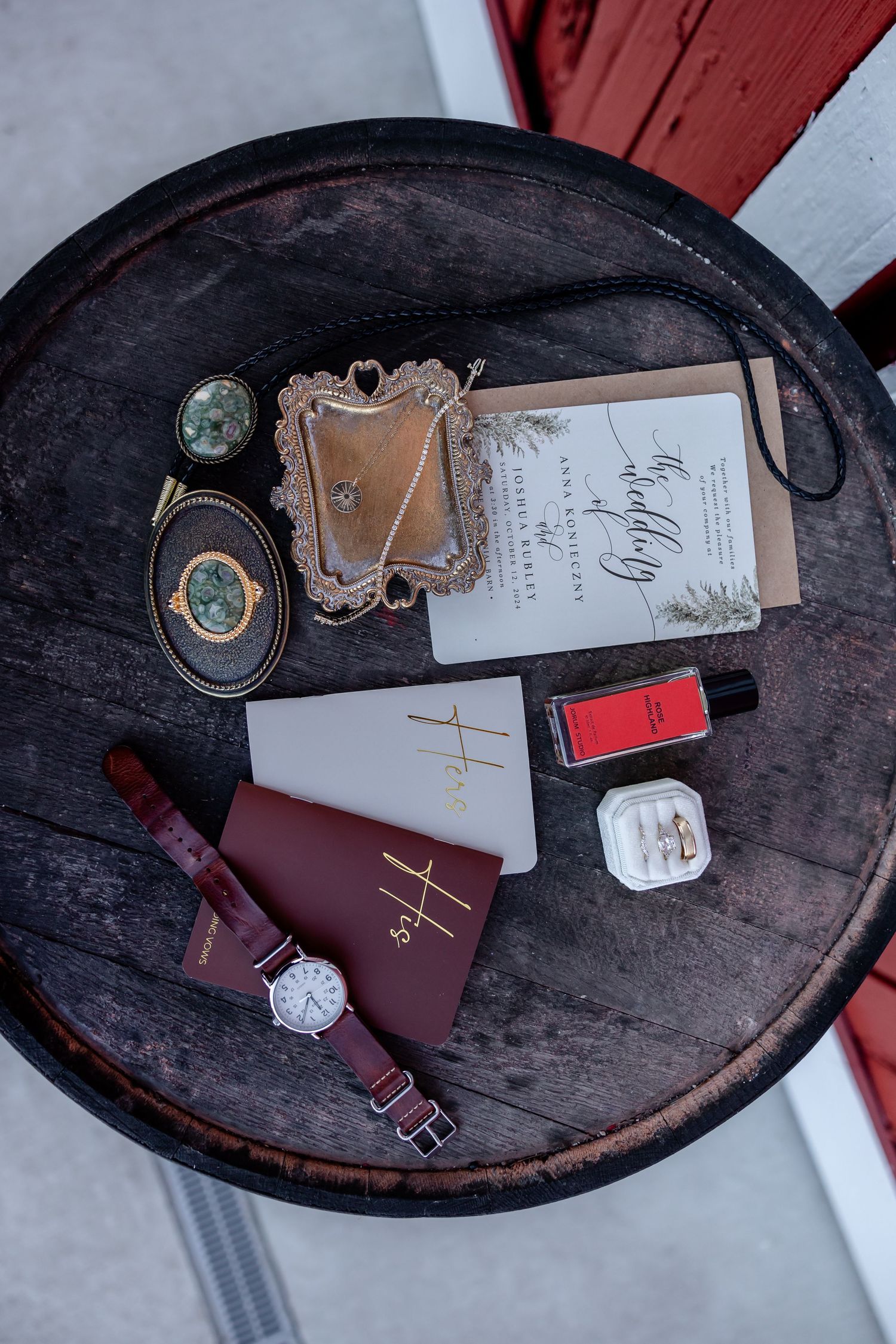 Wedding details including vintage books, rings, and accessories arranged on dark wooden surface.