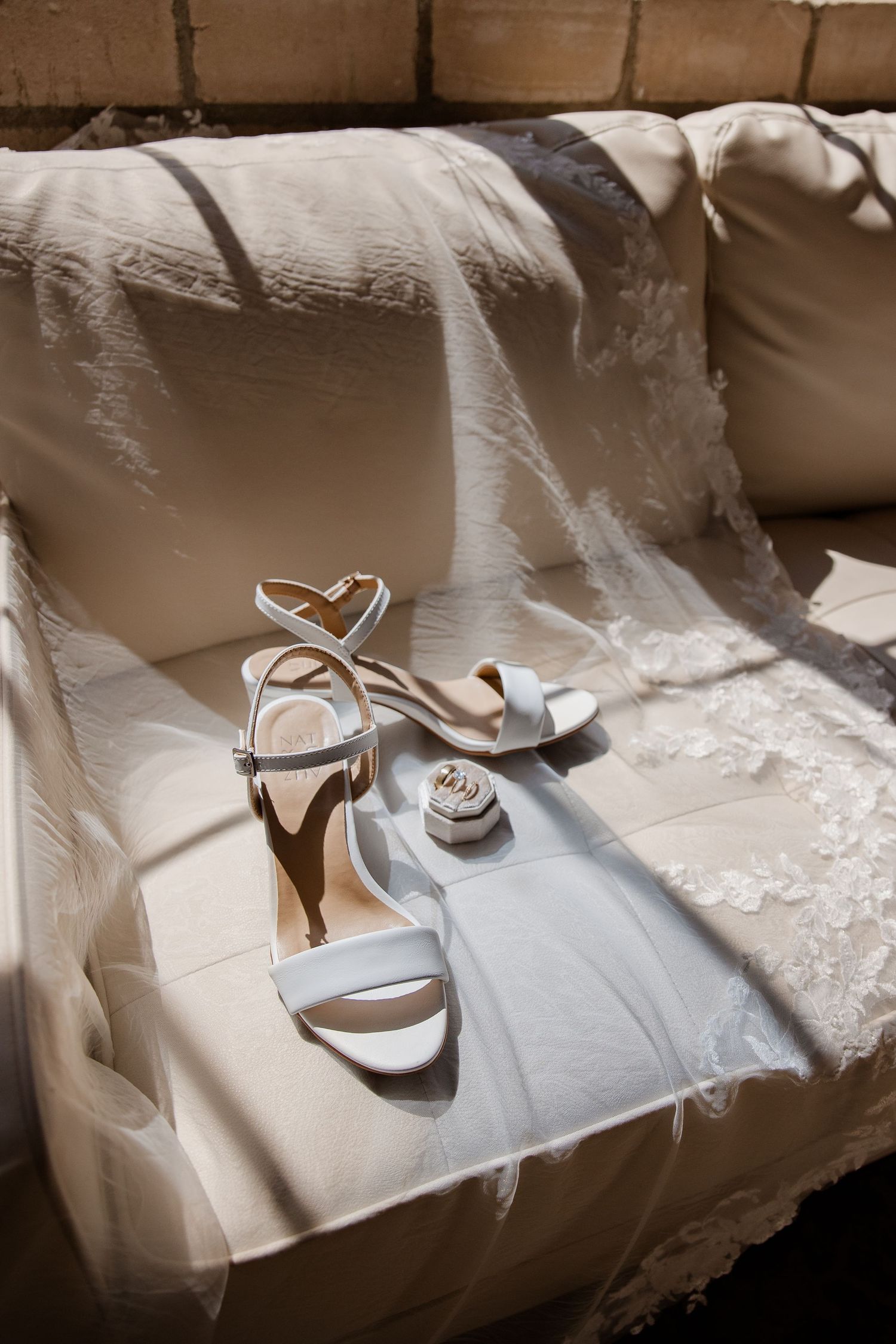 Wedding shoes and accessories arranged artistically in natural window light.