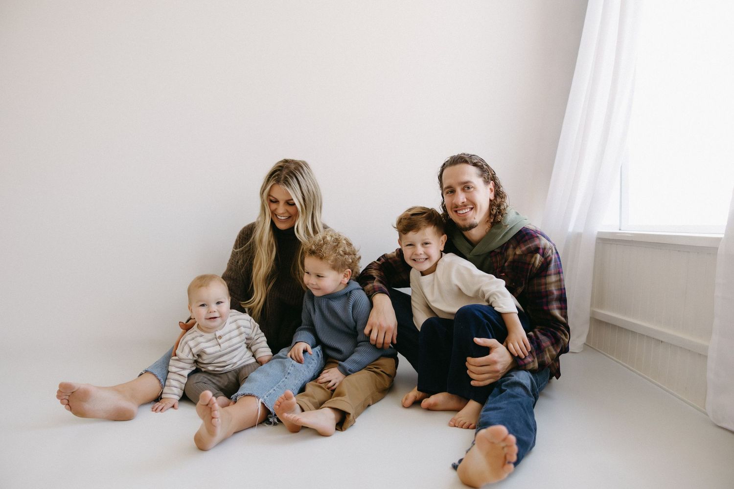 Family members relaxing together on a white floor in casual clothing, creating a cozy and intimate atmosphere.