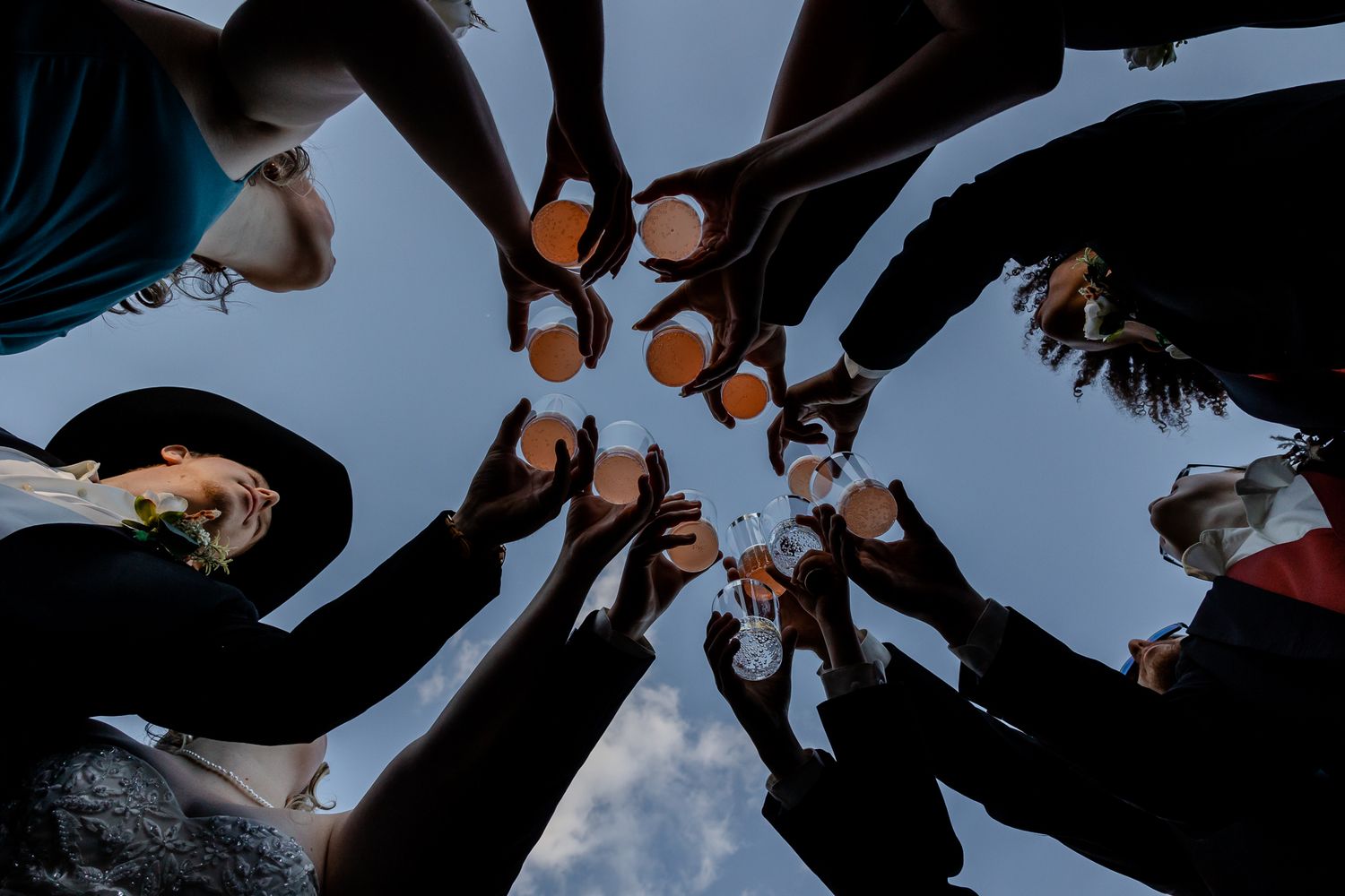 Creative upward angle shot of wedding guests forming a circle against blue sky.