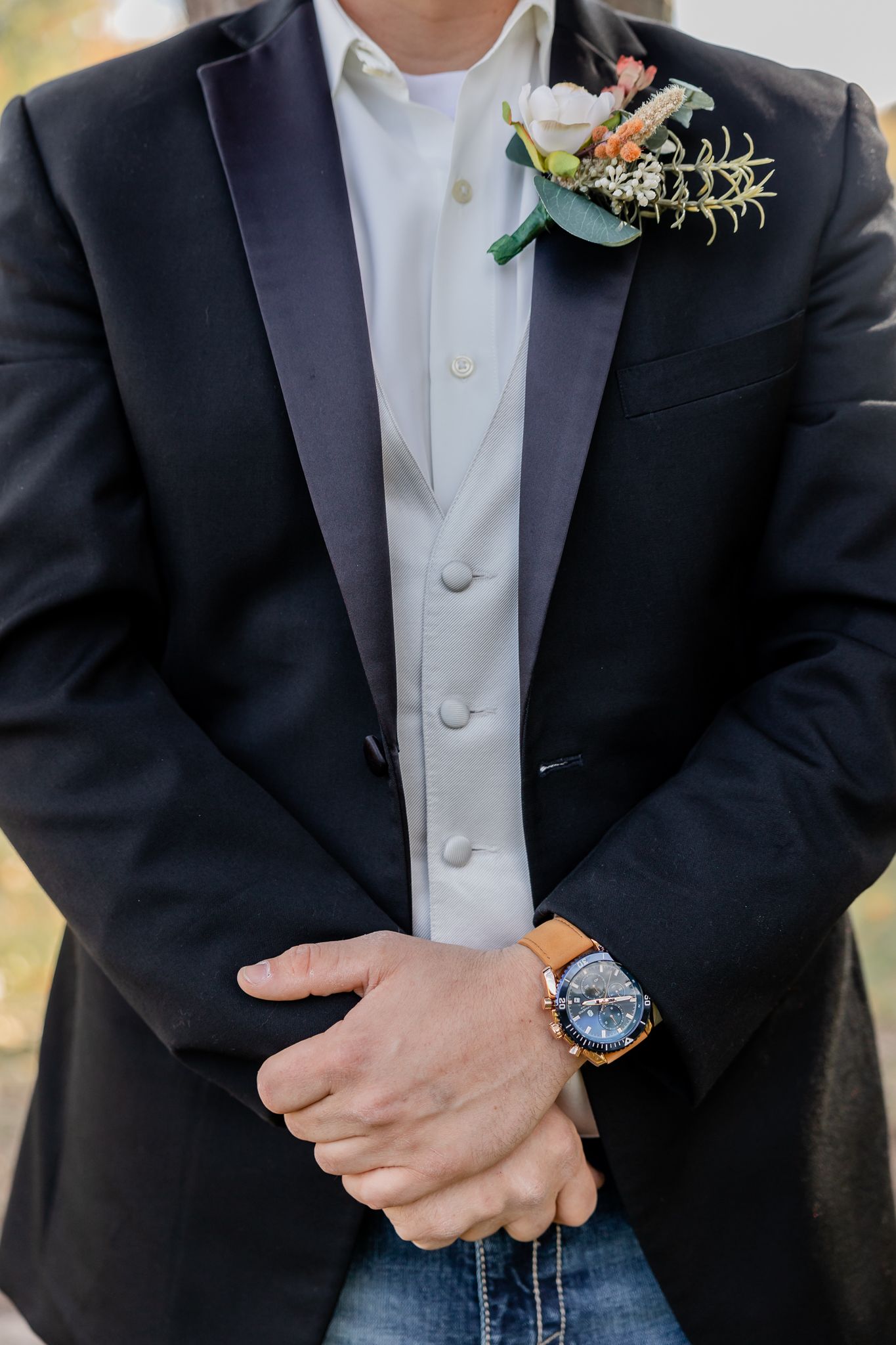 Detail shots of a groom's formal attire showing black suit jacket, white shirt and boutonniere.