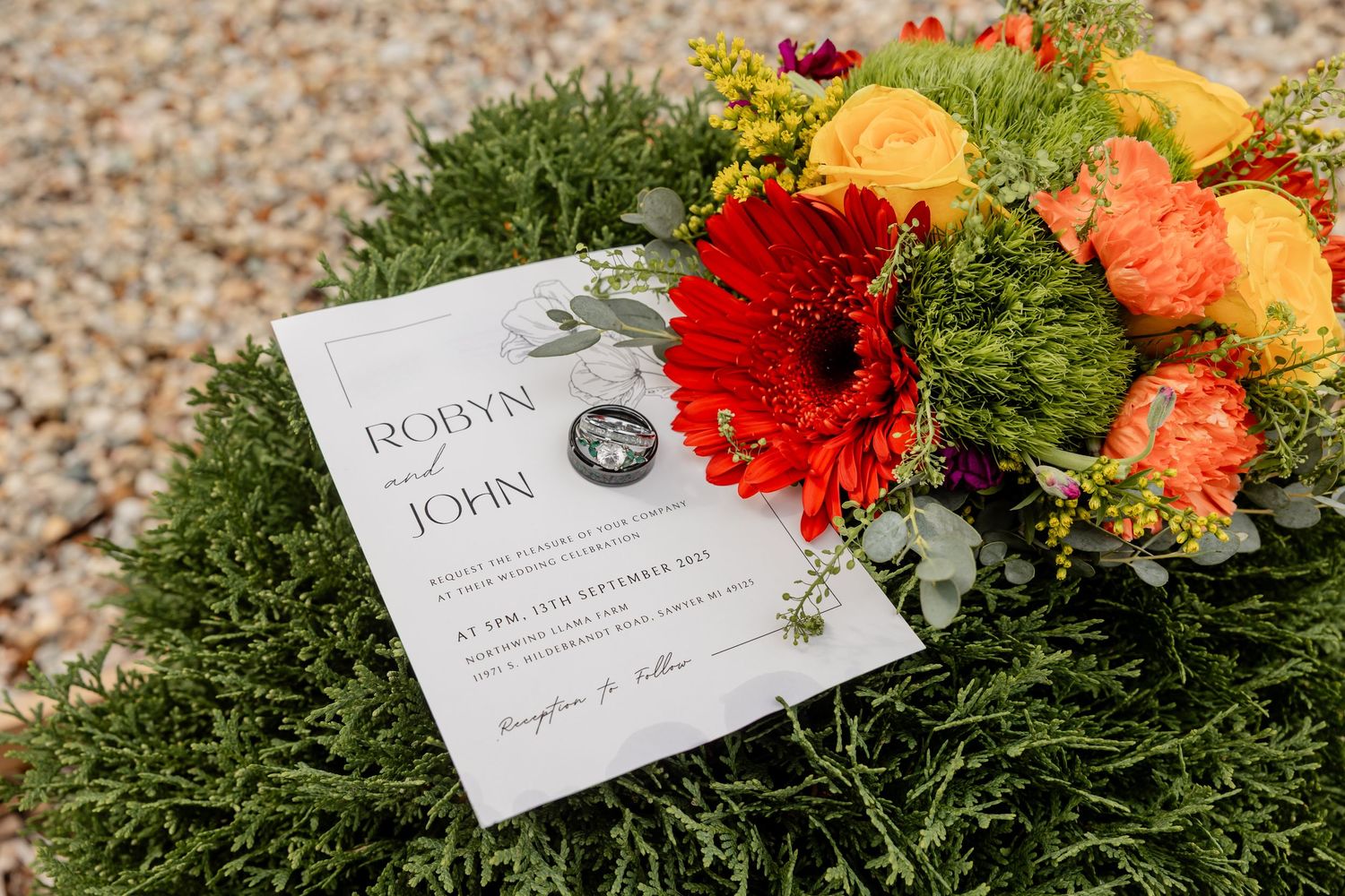 Colorful wedding invitation suite with orange and red florals on greenery backdrop in sawyer, mi