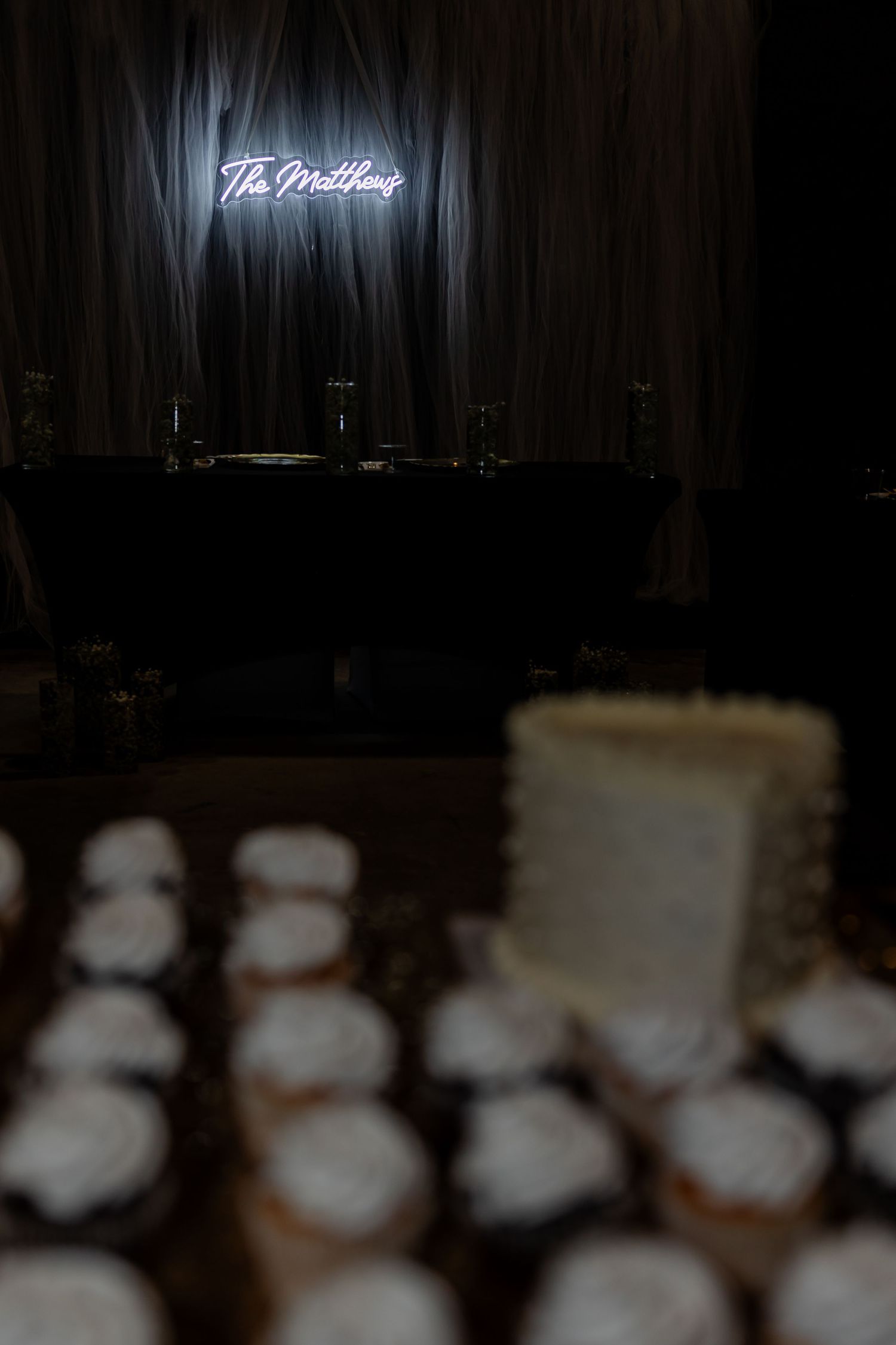 Dark reception setup with neon sign reading 'Til Midnight' above dessert display.