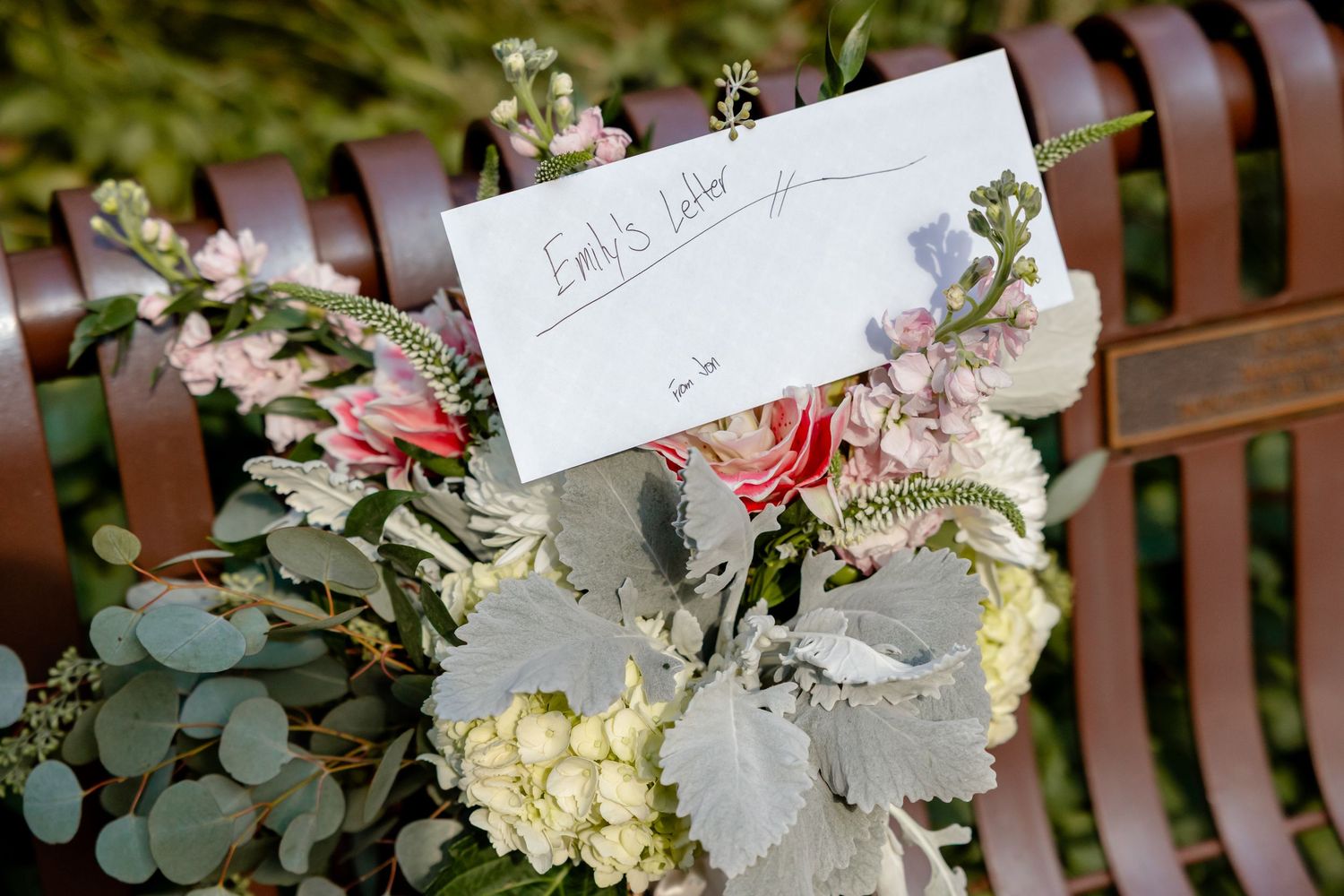 Elegant wedding bouquets with white and blush roses arranged with eucalyptus leaves on a wooden bench.
