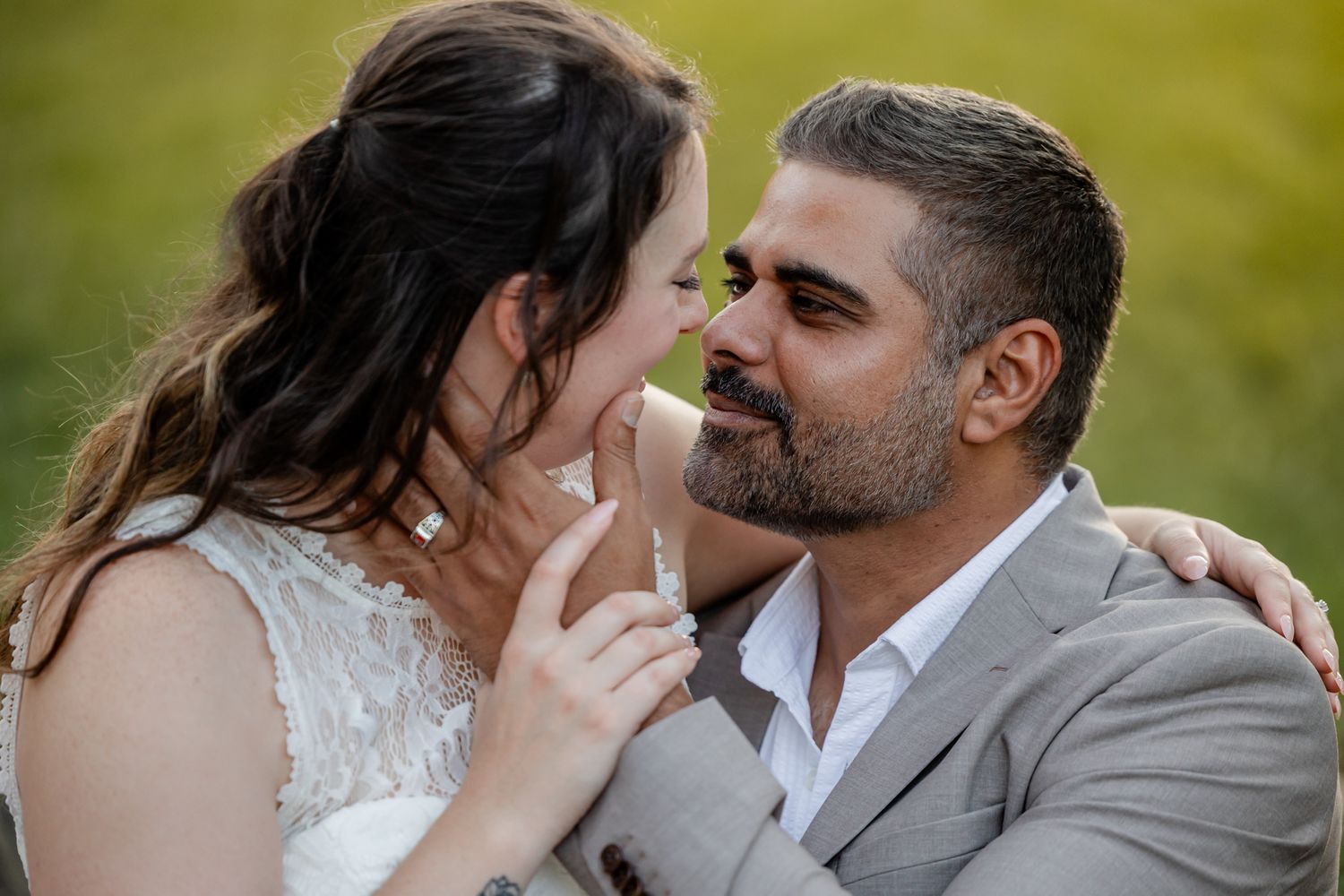 Wedding couple shares intimate moments in a sunlit outdoor setting with bokeh background.