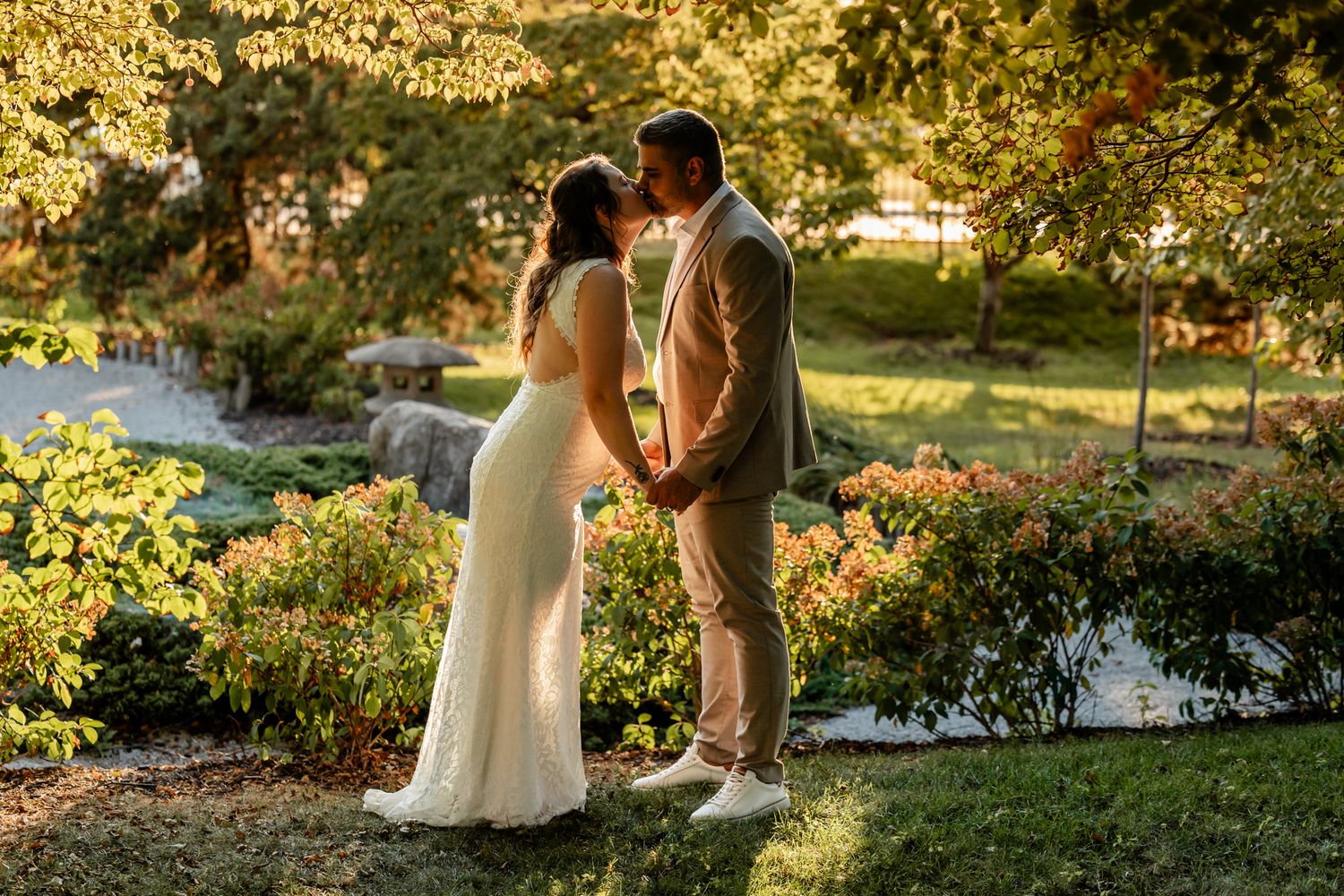 Romantic sunset wedding photos of a couple embracing in a garden setting with golden light filtering through trees.