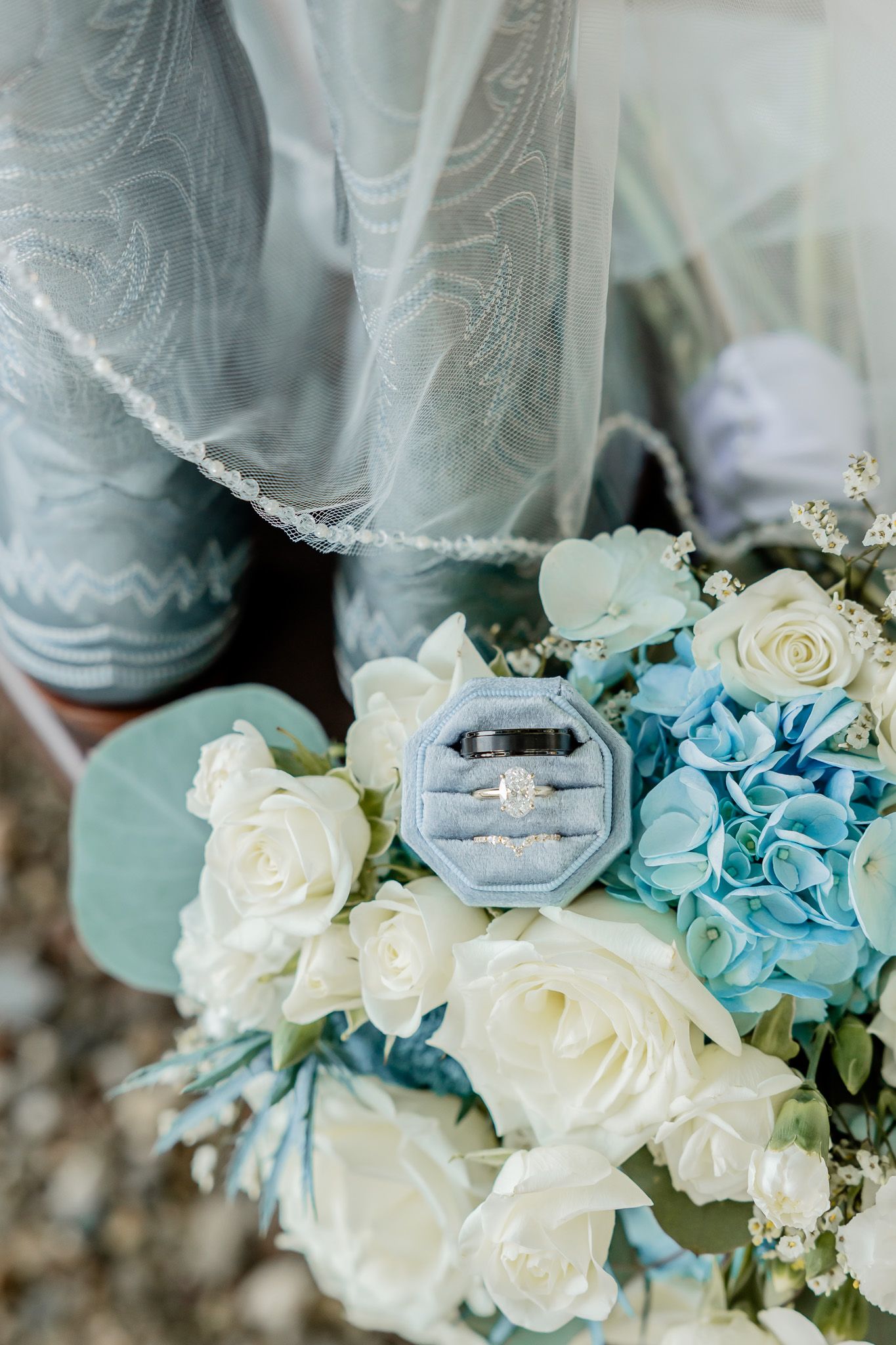 Elegant bridal bouquet featuring white roses and light blue hydrangeas with delicate lace details in a romantic arrangement.