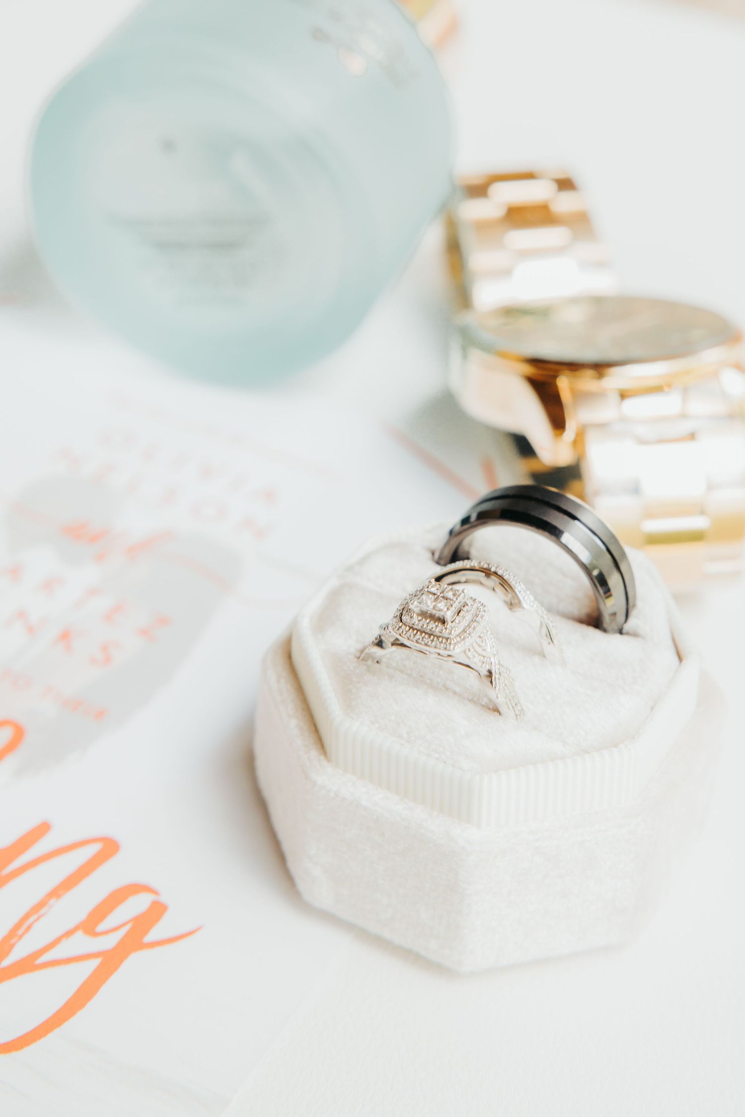 Wedding rings displayed on white hexagonal ring box with soft focus details in background.
