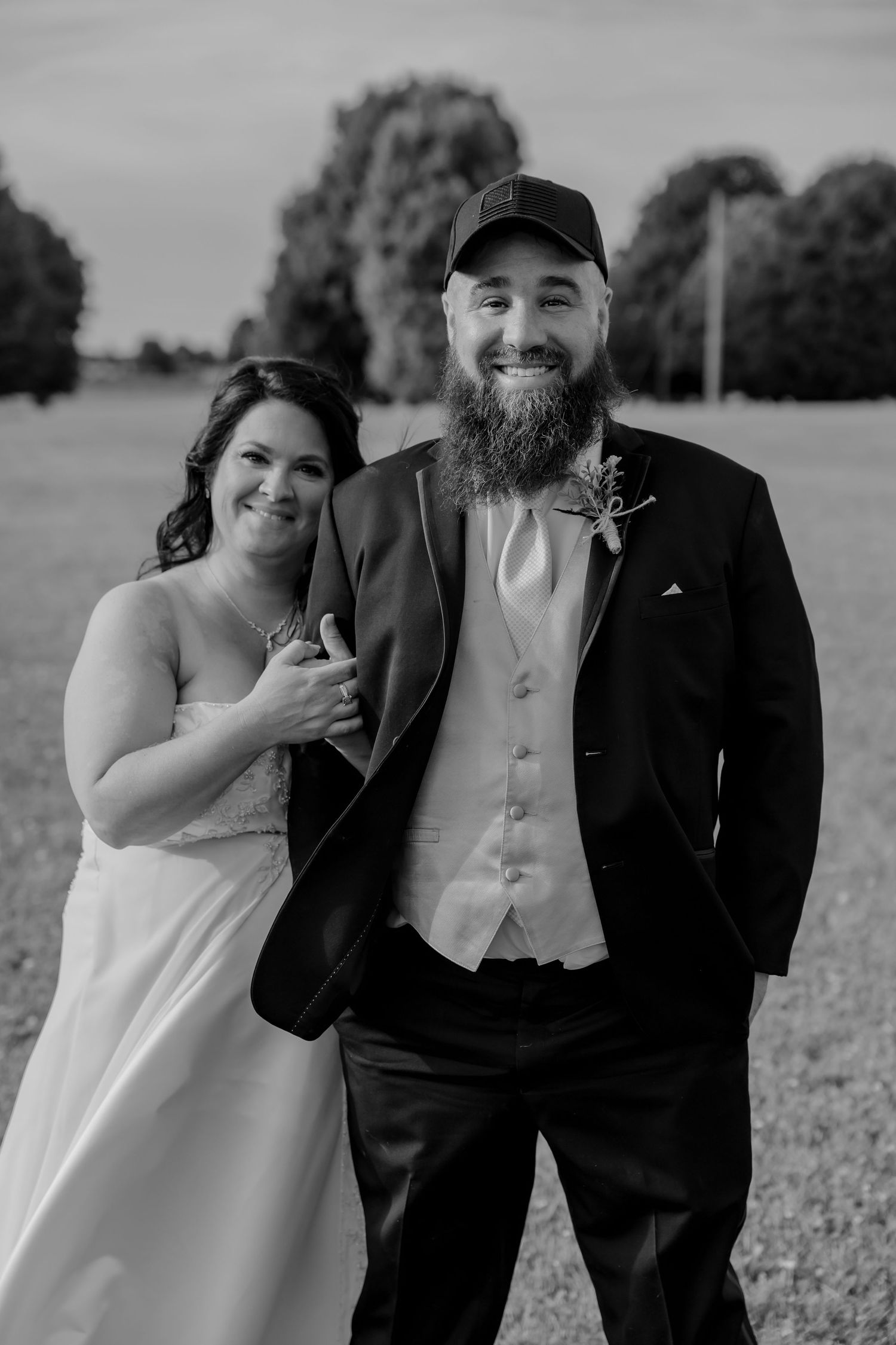 Joyful black and white photo series capturing candid moments of a happy couple embracing and laughing in a field.