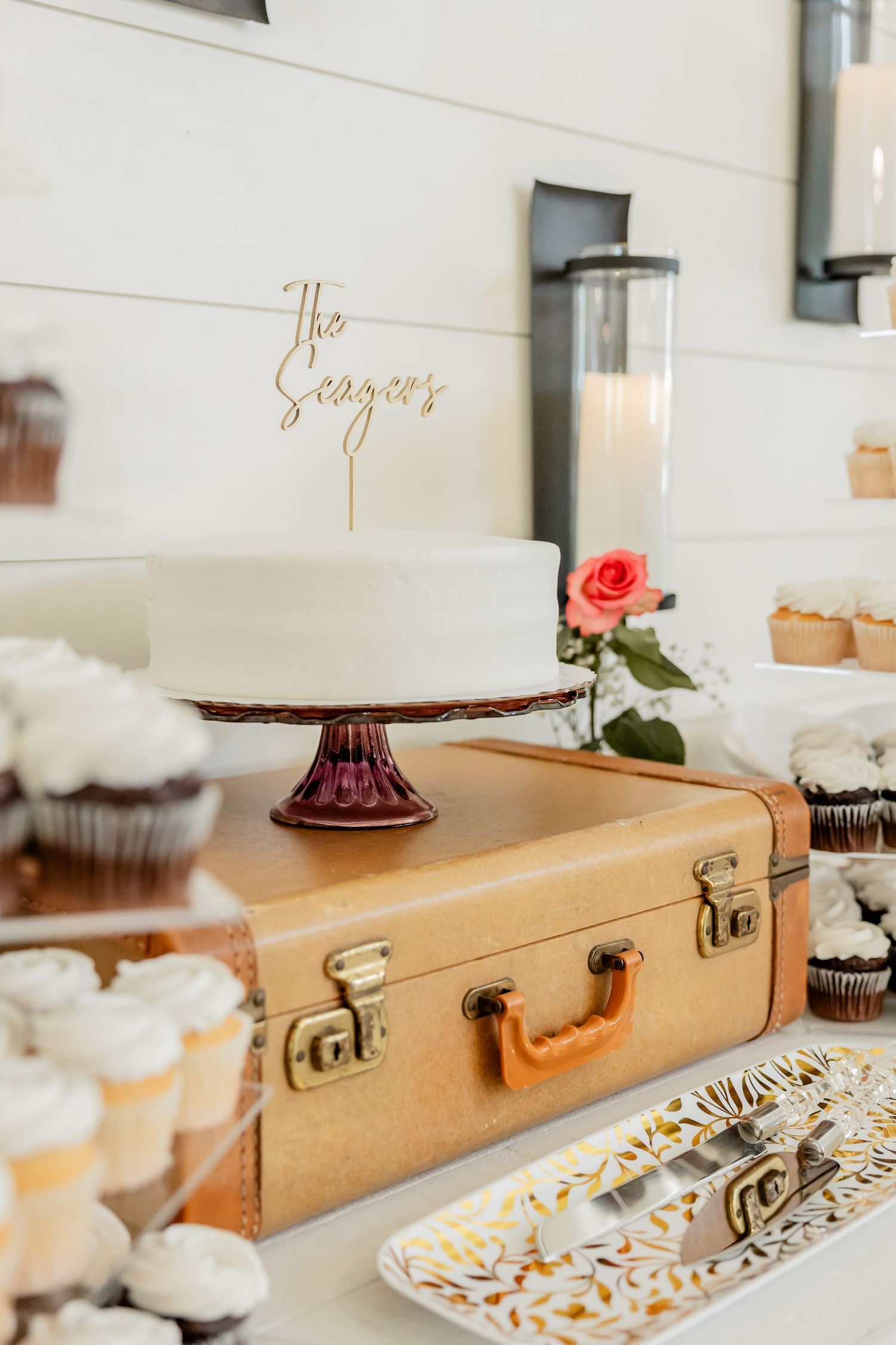 Vintage suitcase serves as rustic wedding decor piece with desserts and decorative displays.