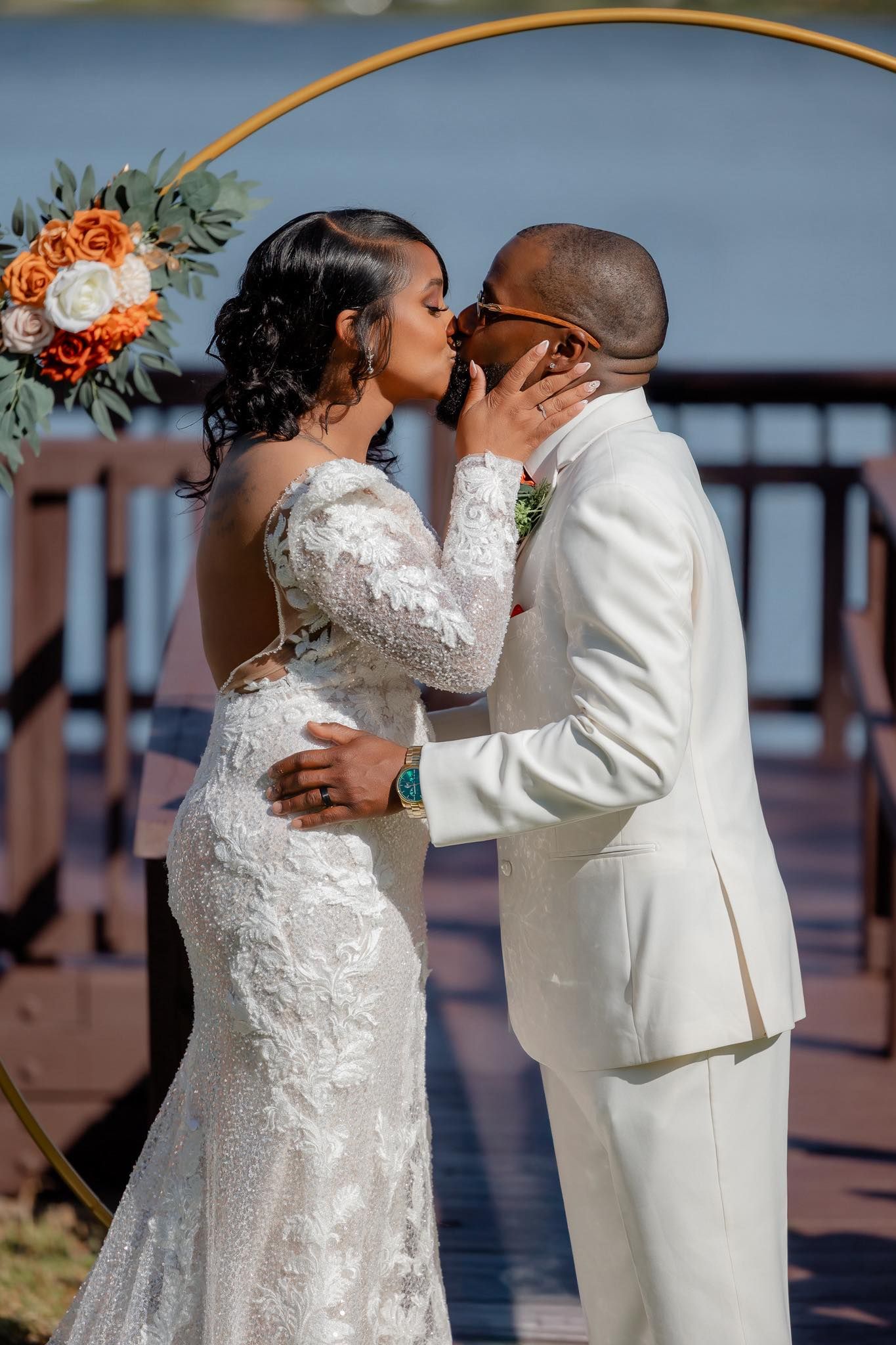 A romantic wedding couple shares intimate moments in white attire against a waterfront backdrop during their special day.
