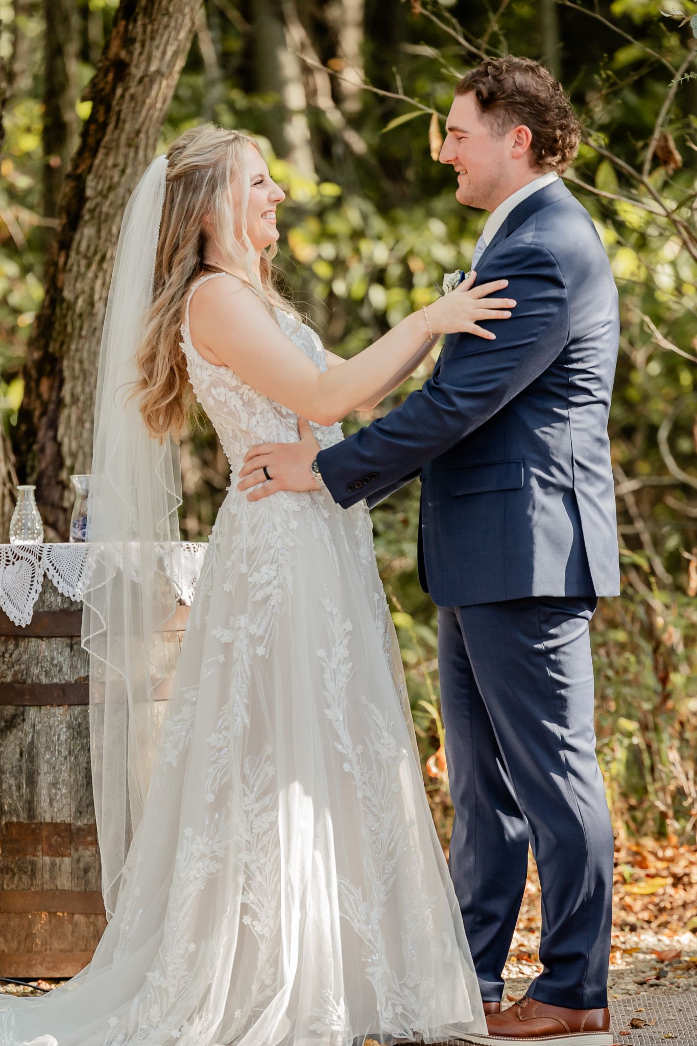 A bride and groom share a joyful moment together outdoors during their autumn wedding ceremony.