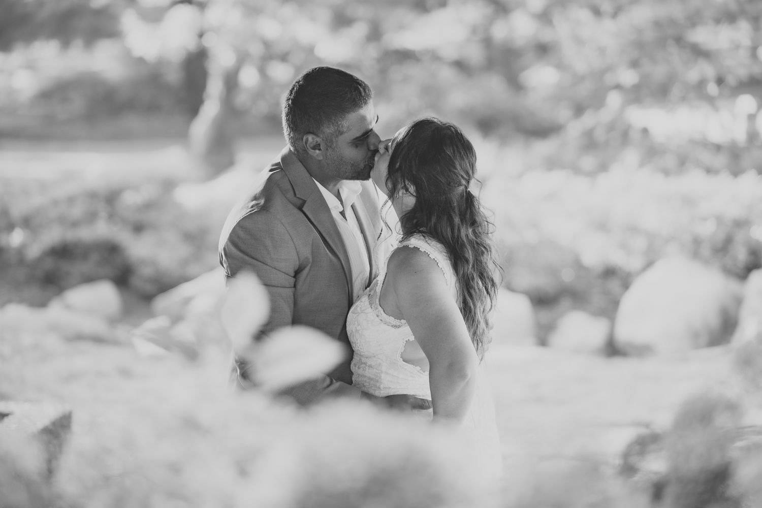 Romantic couple embracing in natural outdoor setting with soft hazy light creating dreamy atmosphere.