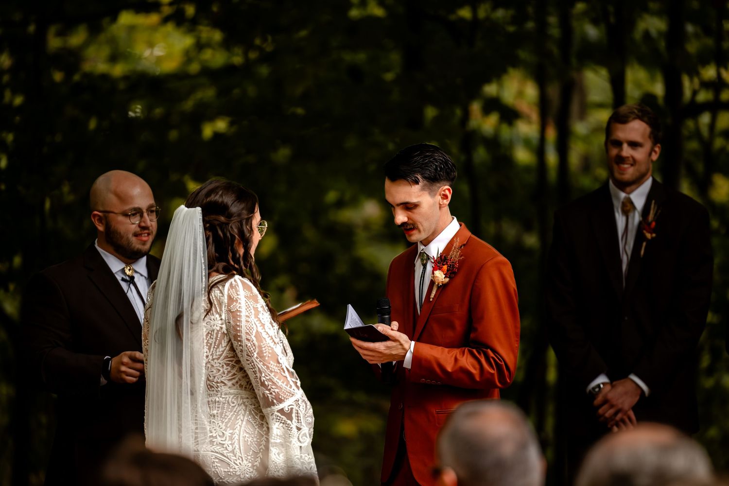 Wedding ceremony guests gathered outdoors during a forest celebration. Centennial Barn