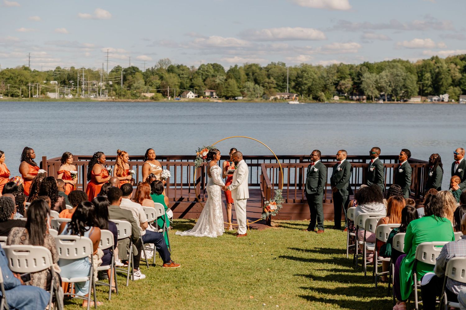 Waterfront wedding ceremony with guests seated in white chairs overlooking the lake.