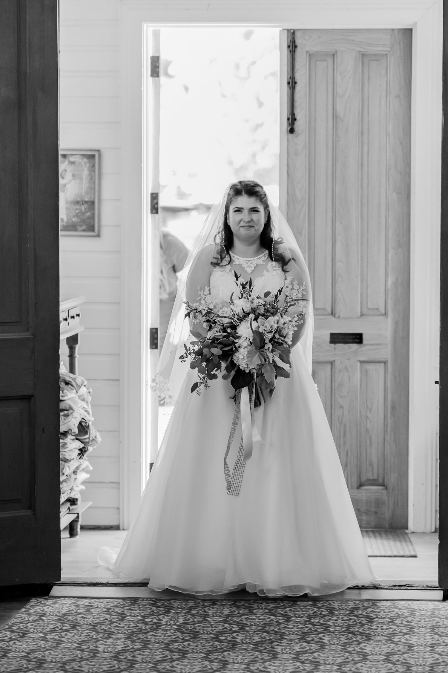 Black and white wedding photo series showing a bride in a flowing white gown holding a bouquet in various doorway poses.