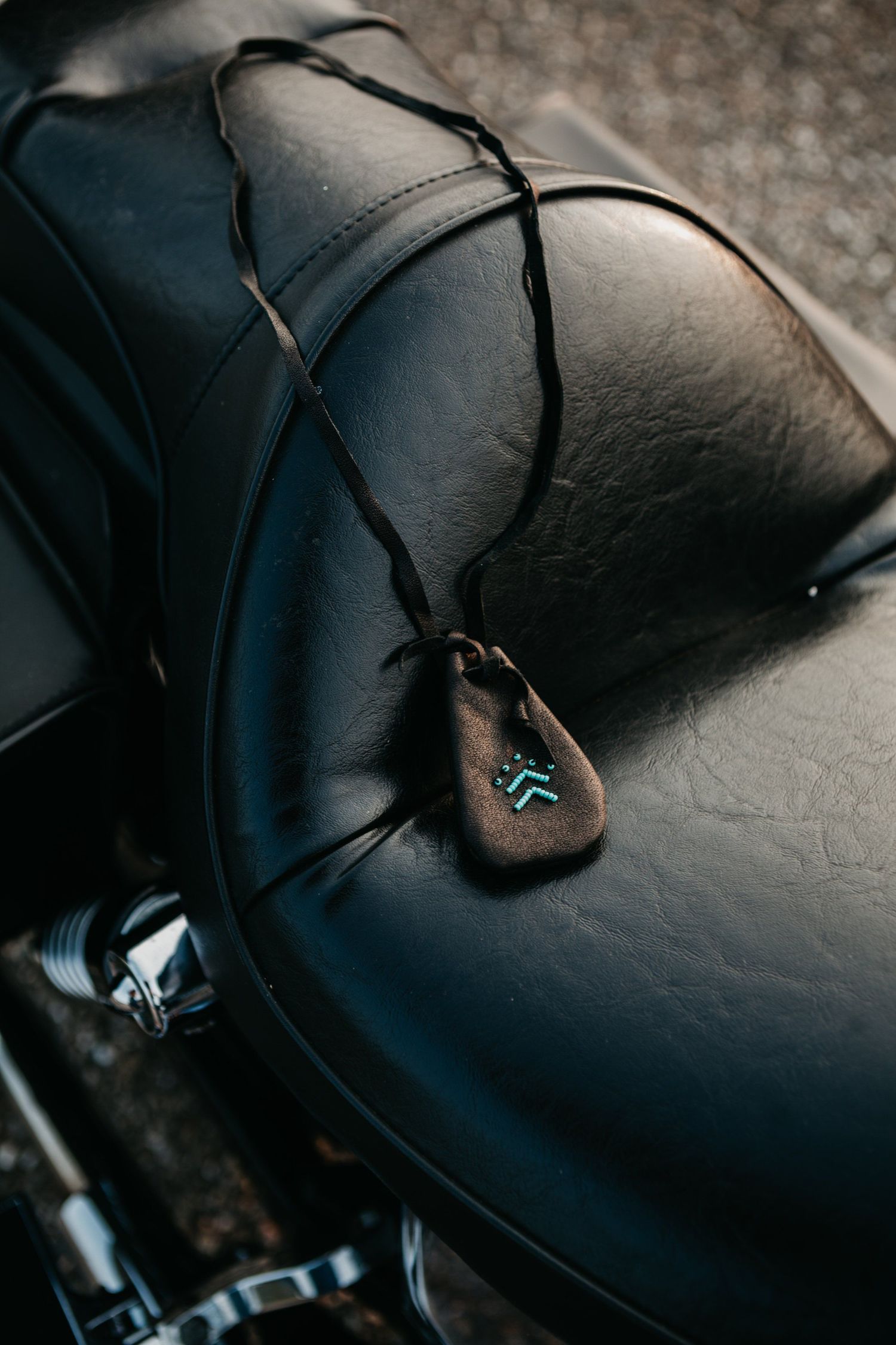 Close-up detail of black leather motorcycle seat with decorative stitching.