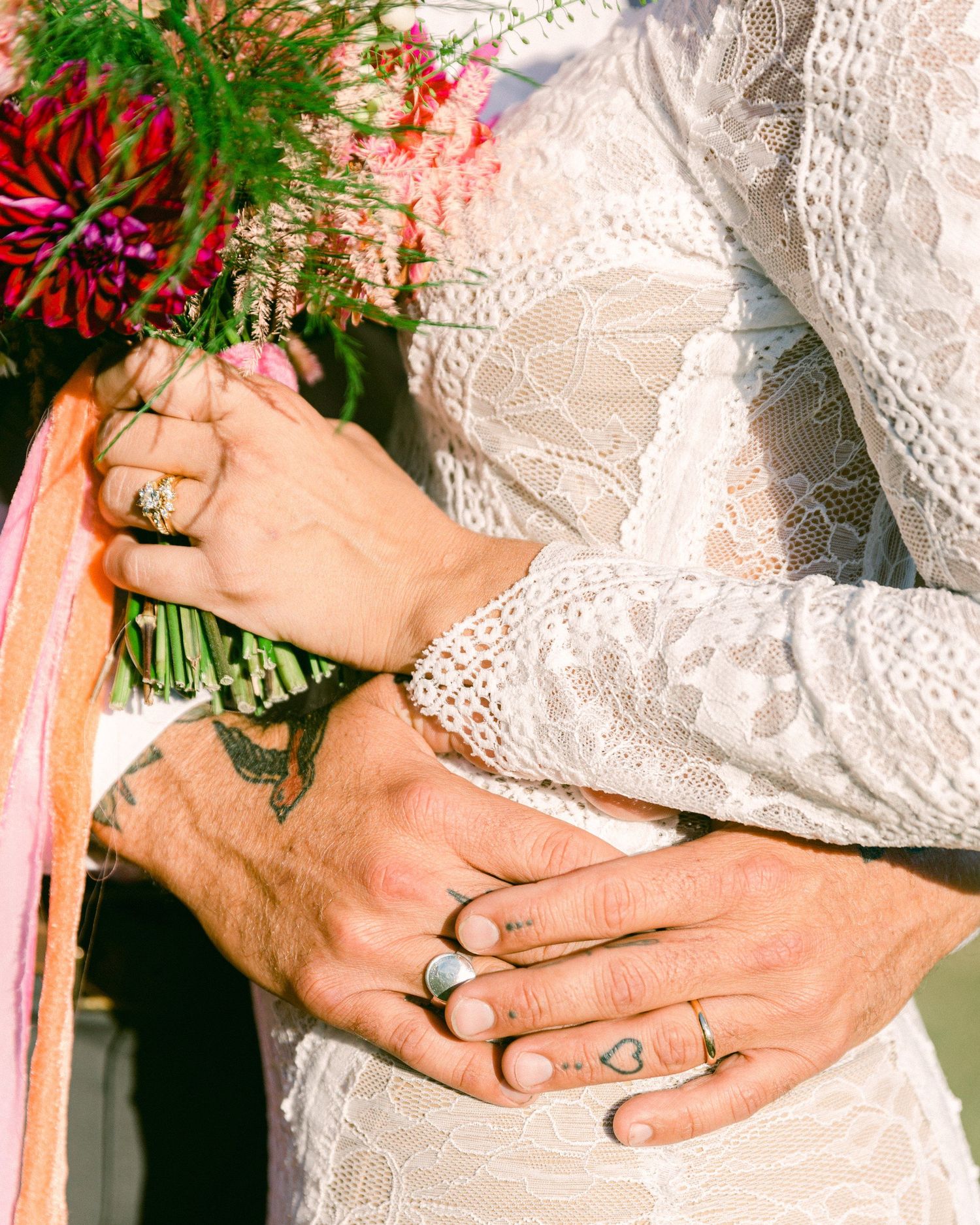 Close-up of wedding rings and lace details from a bride's dress.