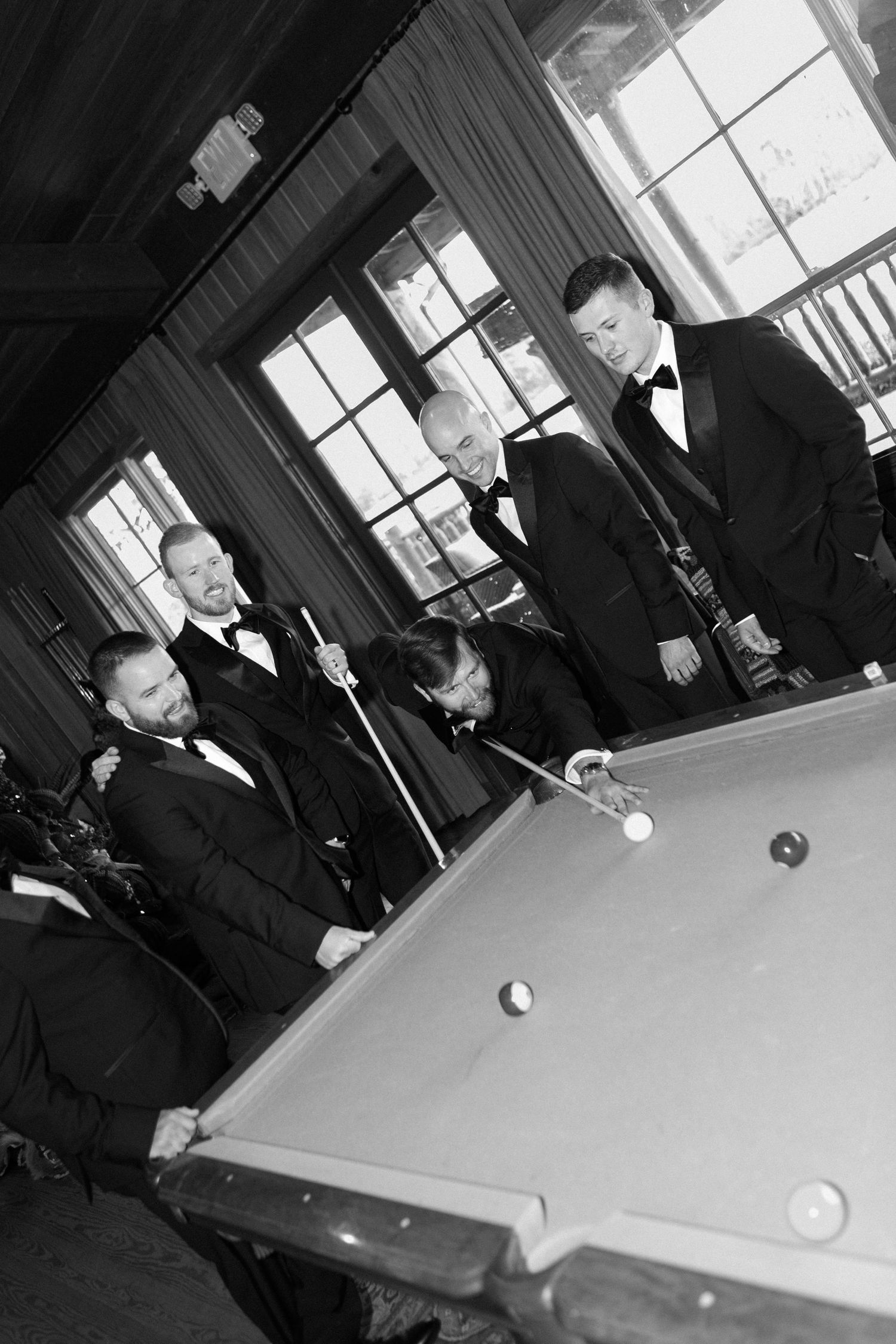 Black and white photos of groomsmen playing pool before wedding ceremony.