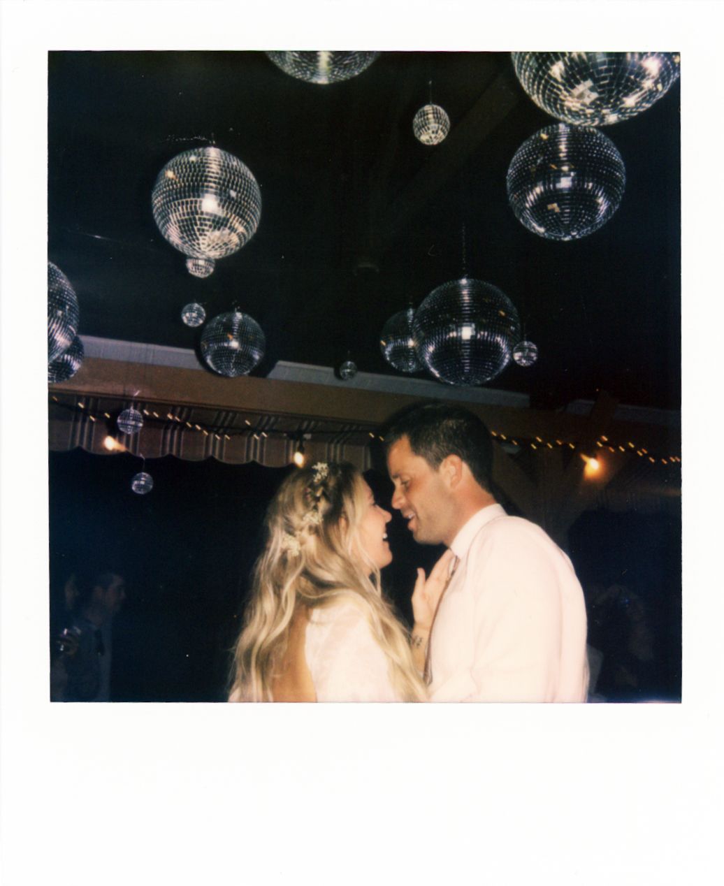 Romantic dance under disco balls at wedding reception.