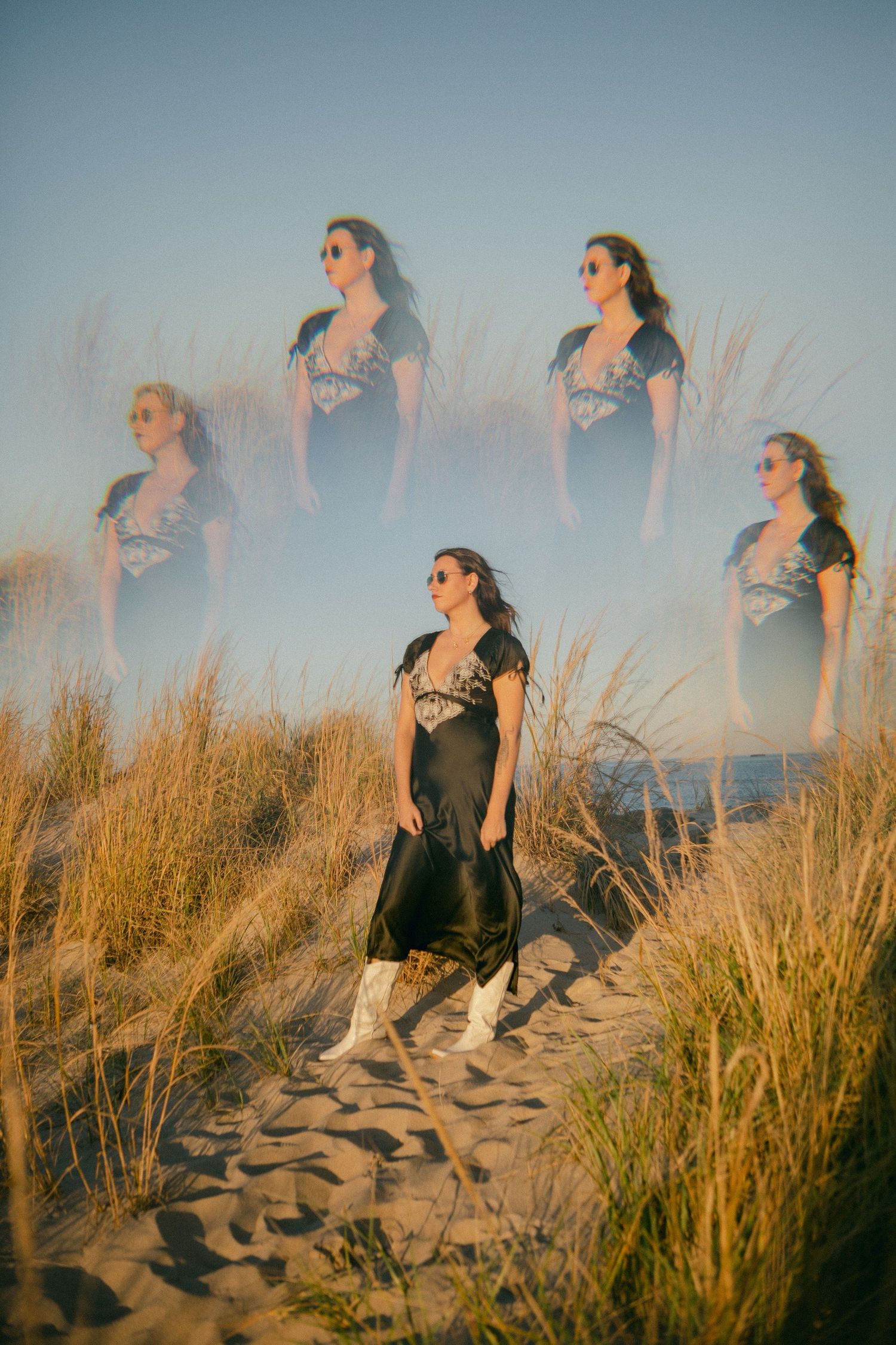 People walking along sandy beach dunes at golden hour.
