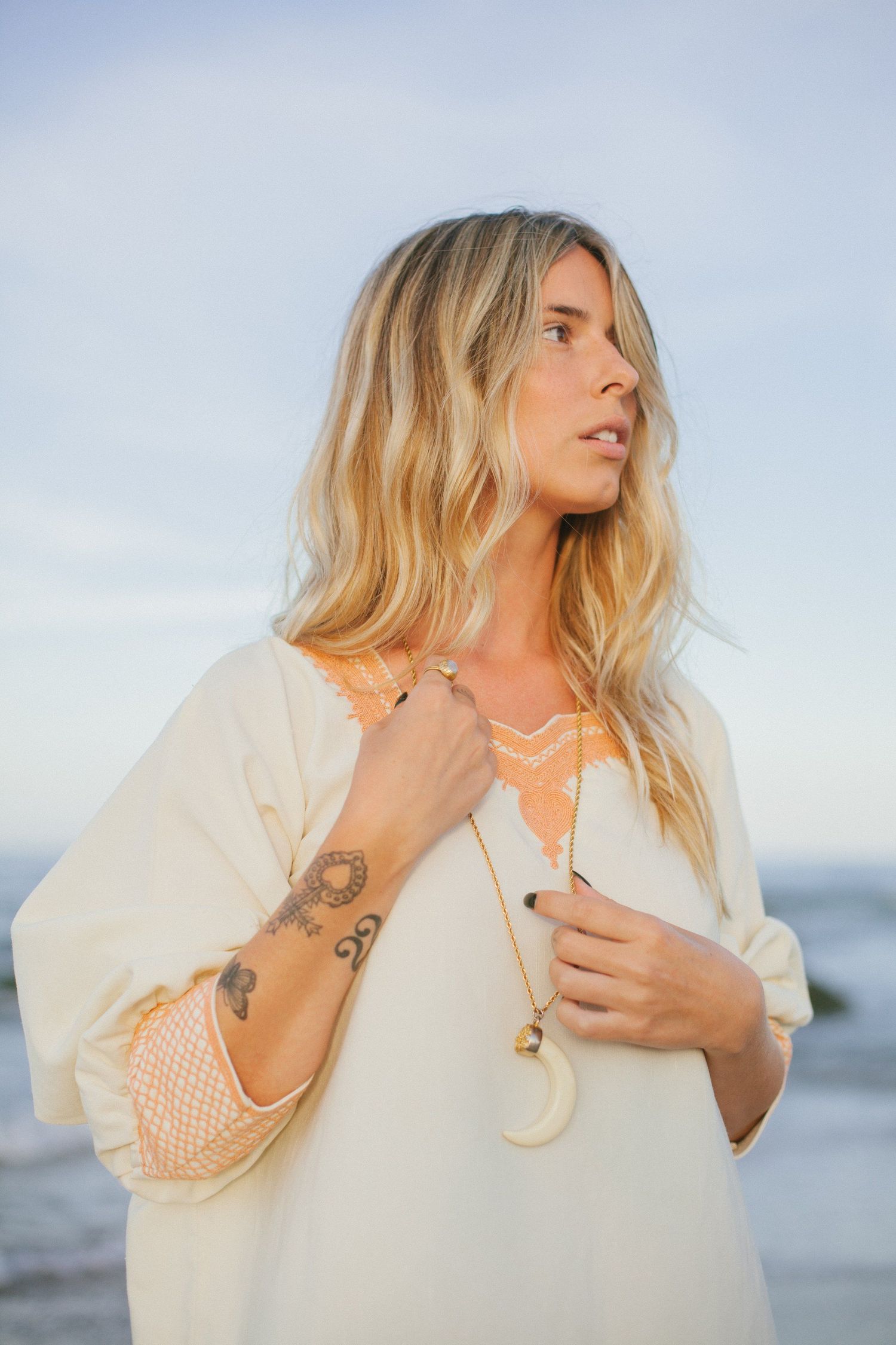 Seaside fashion portraits featuring person in cream colored top with jewelry.