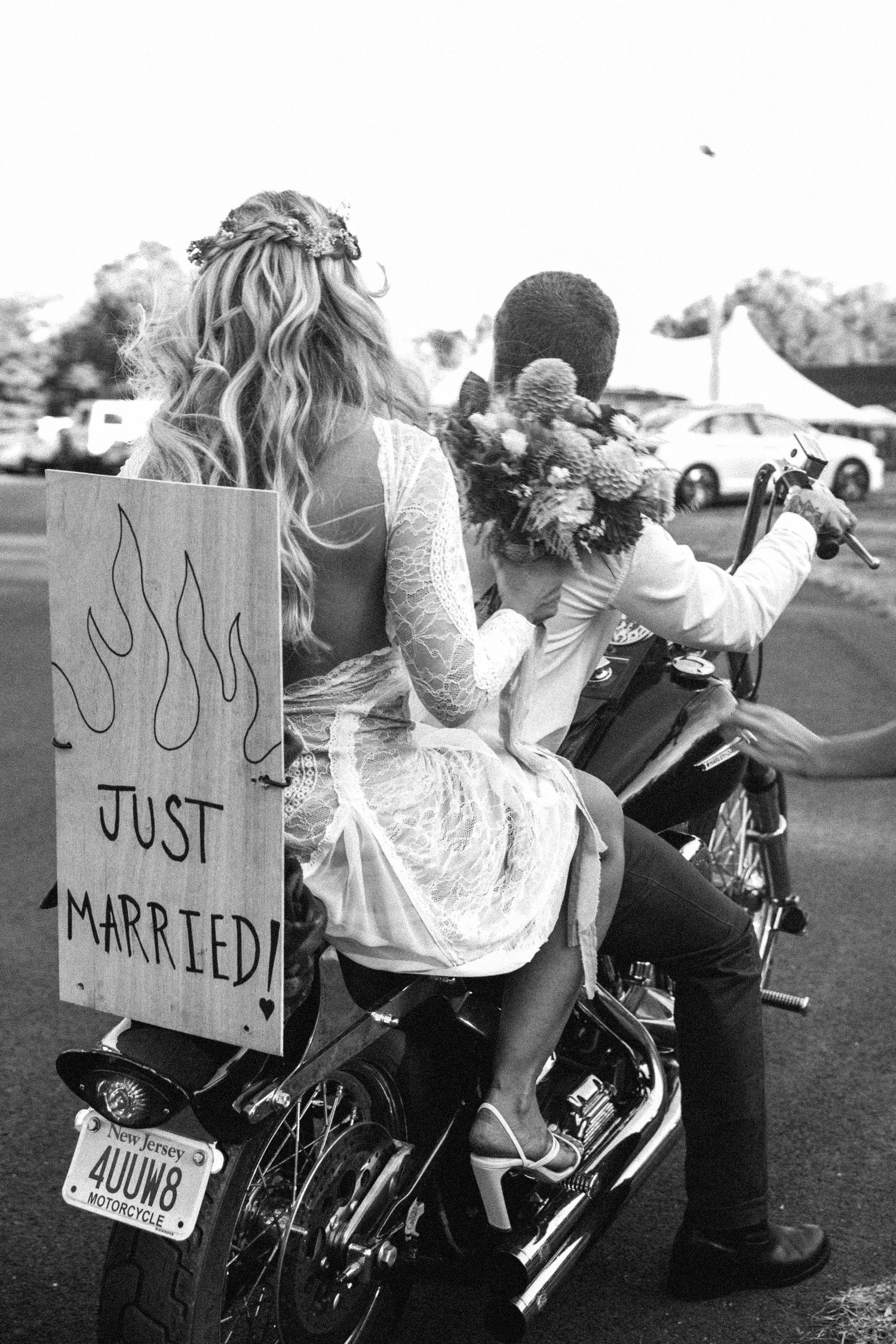 Newlyweds on motorcycles with 'Just Married' signs in black and white photography.