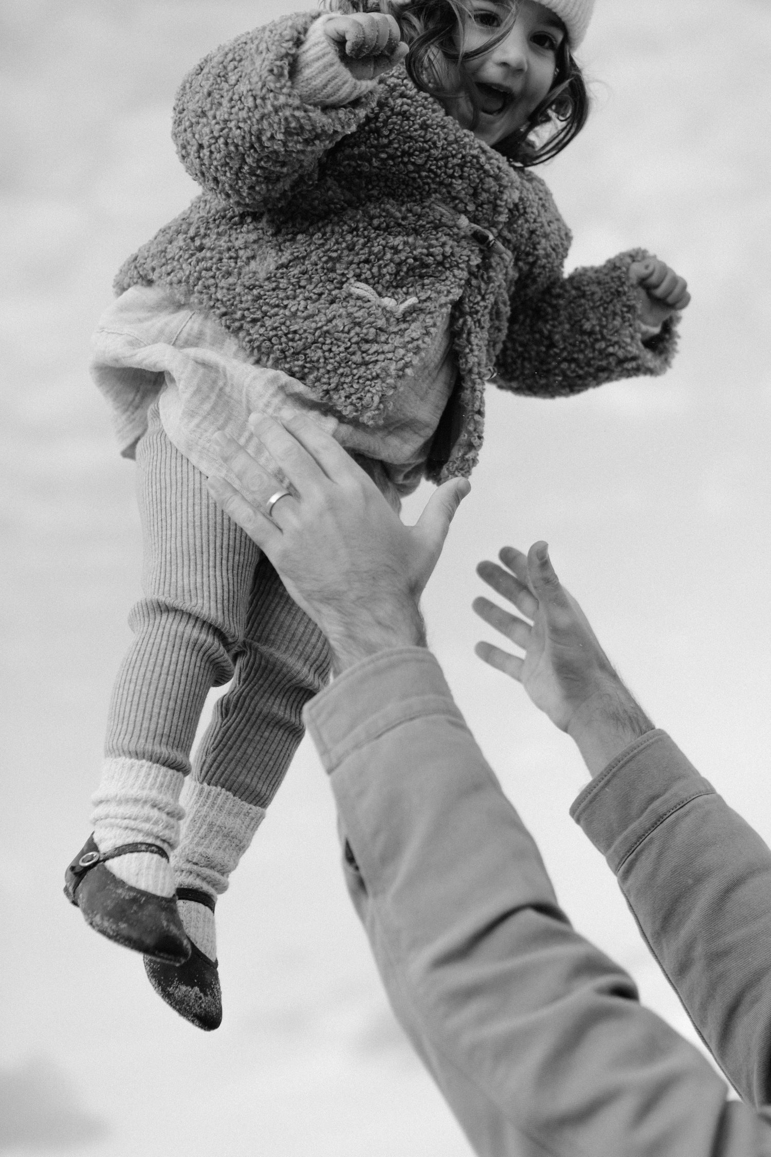 Black and white sequence of a baby being lifted up in cozy winter clothing.