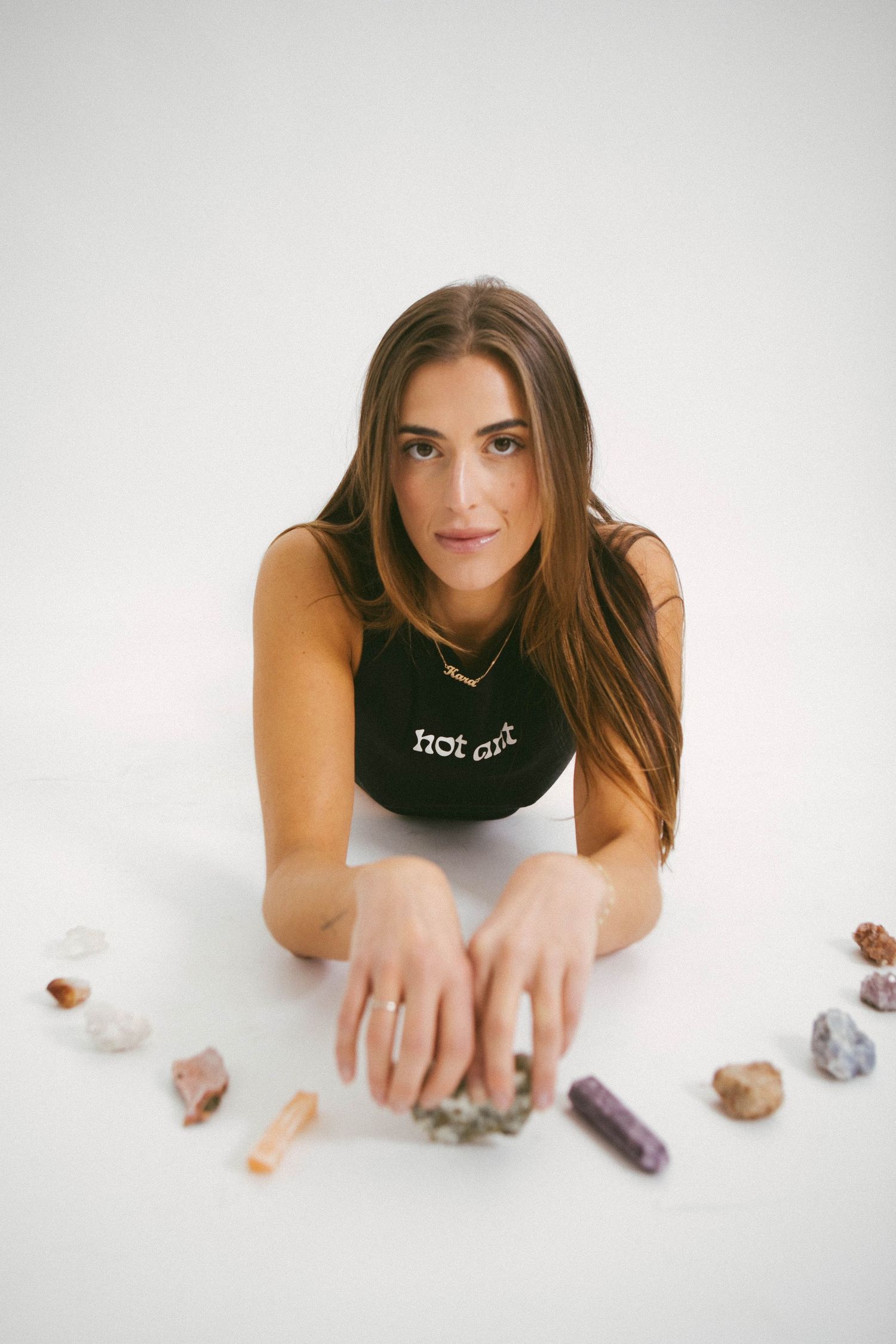 Person in black crop top arranging crystals and stones on white surface.
