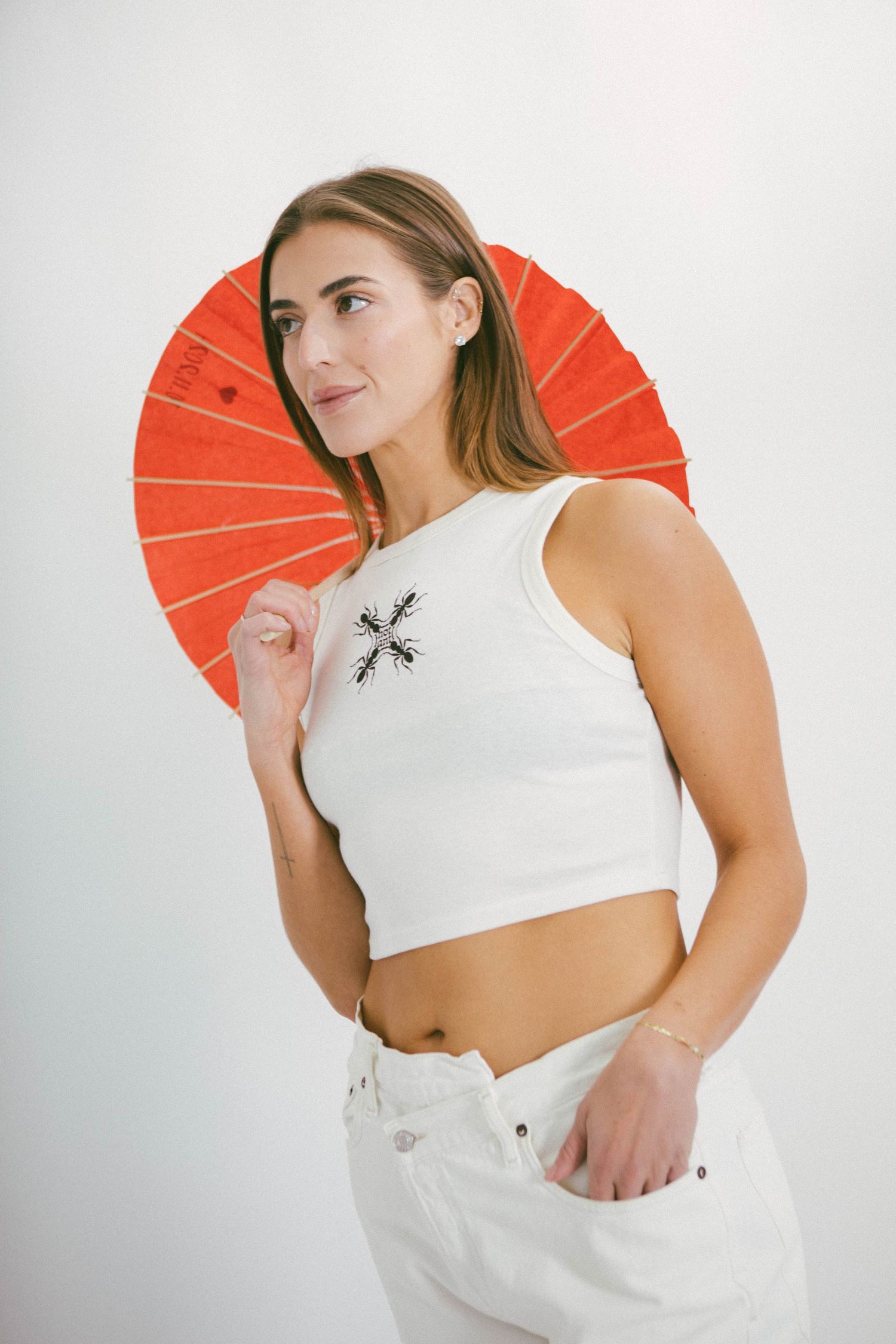 Fashion portrait with white crop top against orange fan backdrop.
