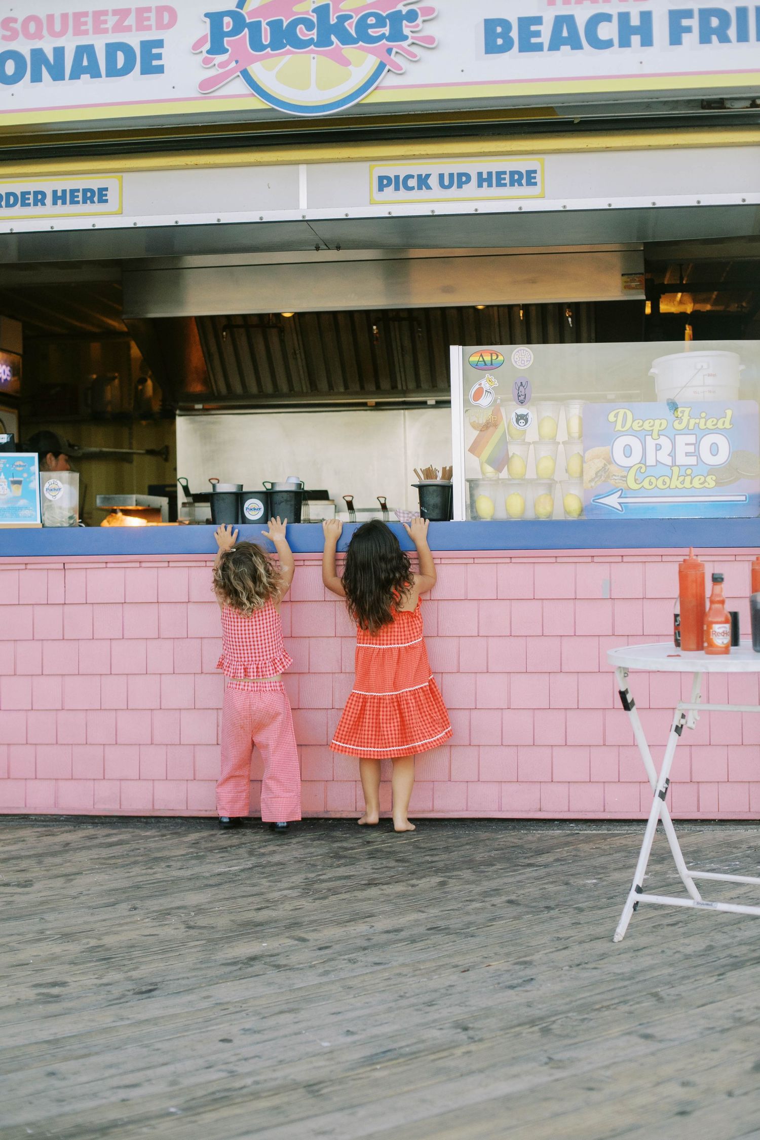 Pink retro ice cream stand with customers waiting at service window.