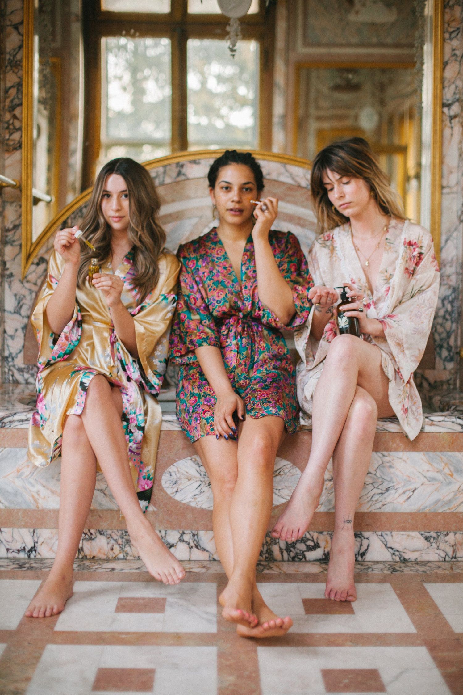 Group of friends in floral dresses sitting together on a porch.