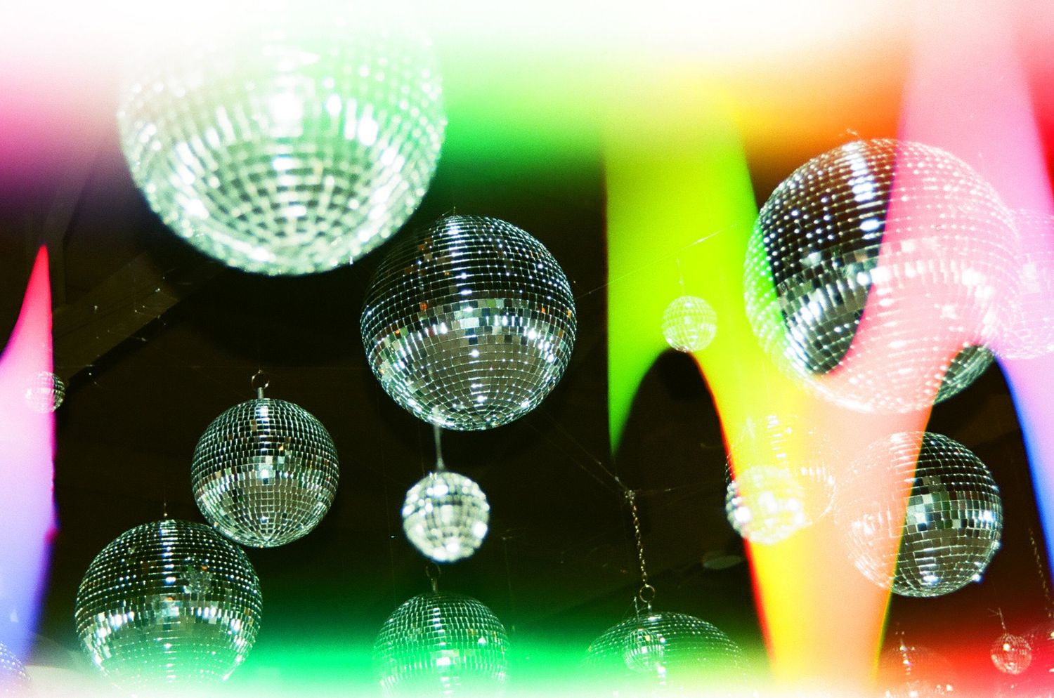 Disco balls hanging from ceiling with colorful party lighting effects.