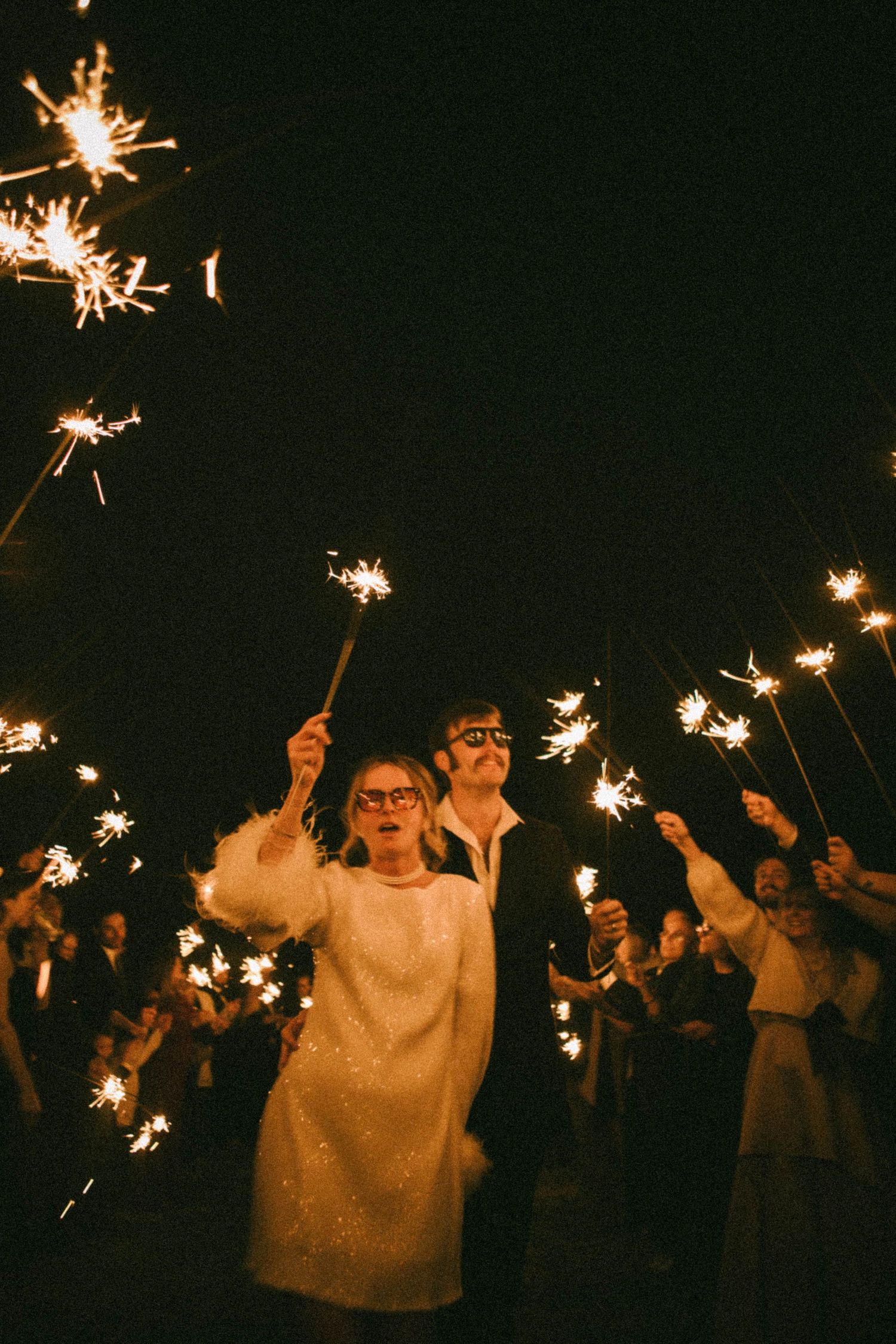Nighttime celebration with sparklers creating magical light trails among party guests.