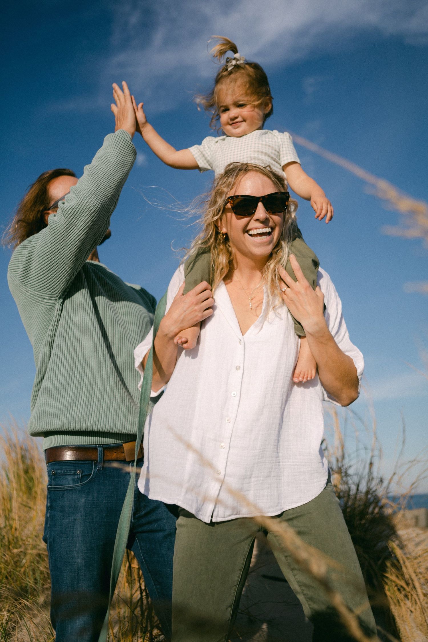 Joyful friends laughing and playing outdoors against a bright blue sky.