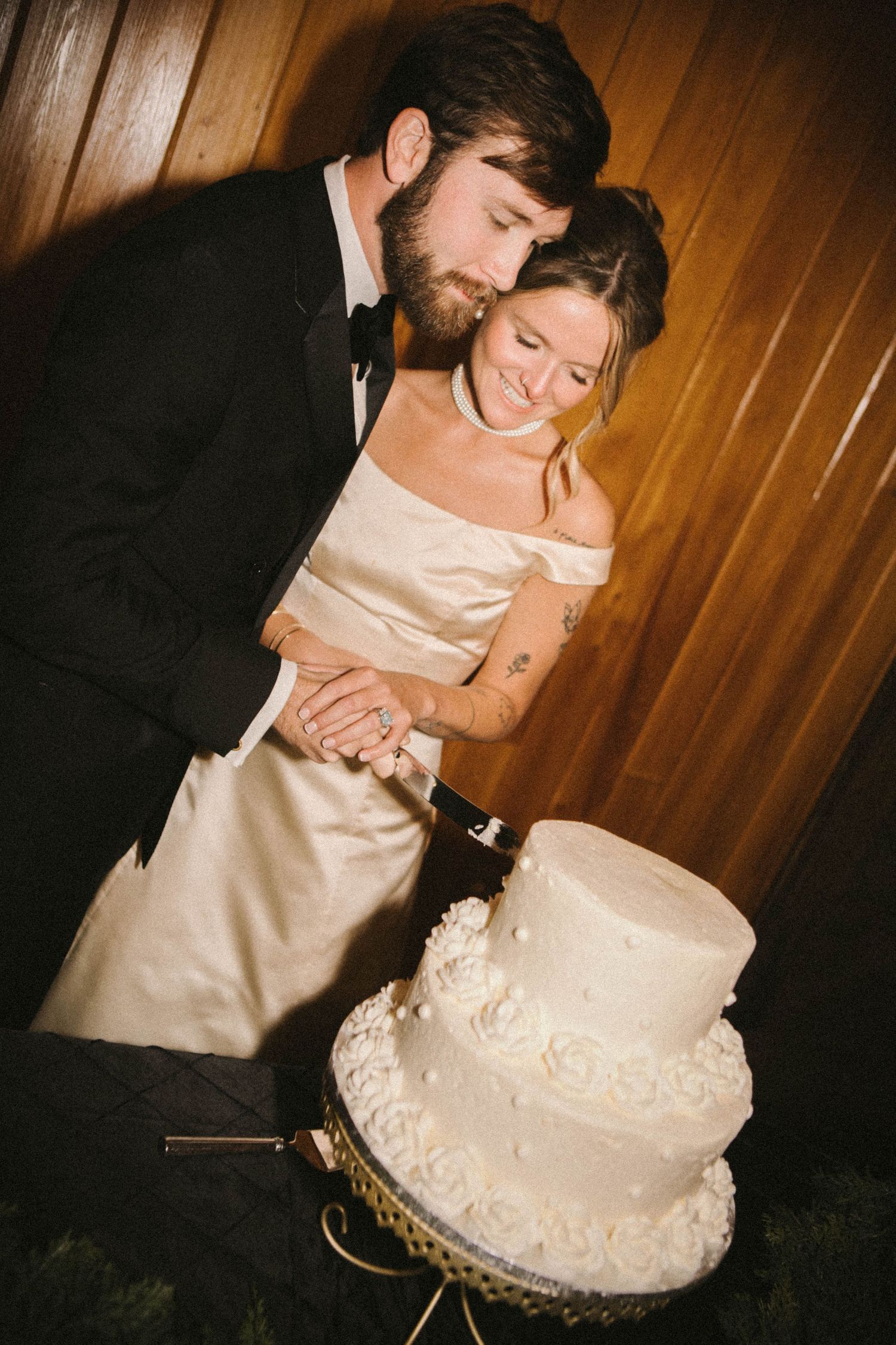 Newlyweds cutting their elegant white wedding cake together at reception.