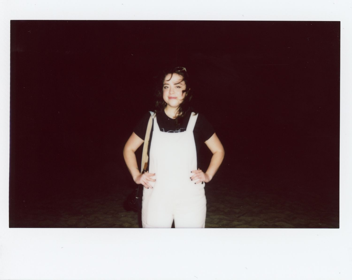 Vintage polaroid style photo of person in white overalls at night.